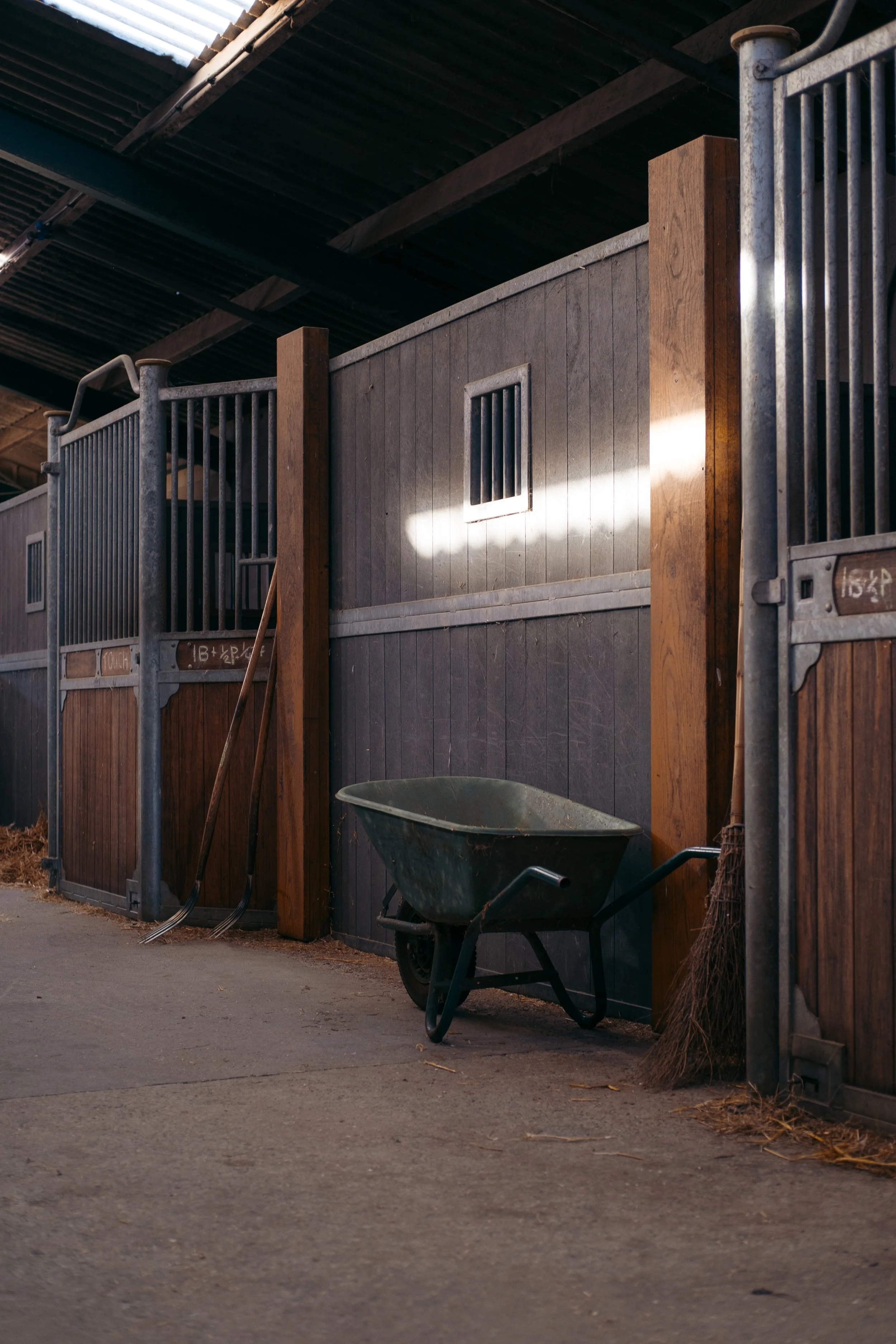 Interieur van een paardenstal met stro, houten balken en zacht licht
