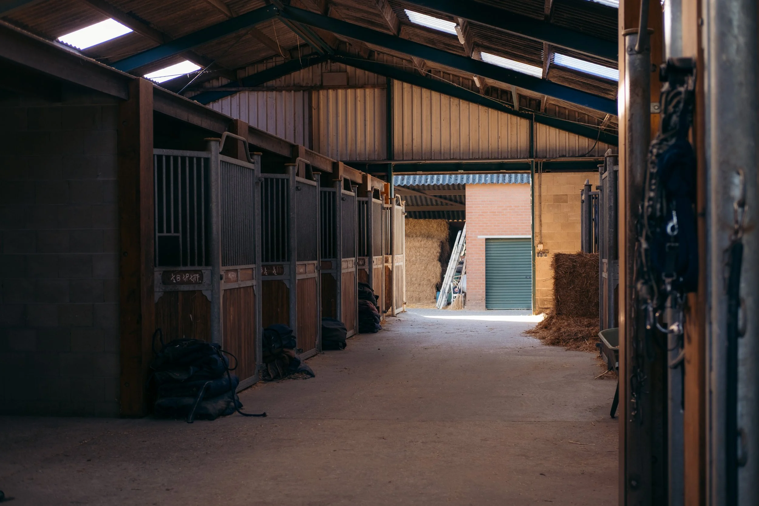 Interieur van een paardenstal met stro, houten balken en zacht licht