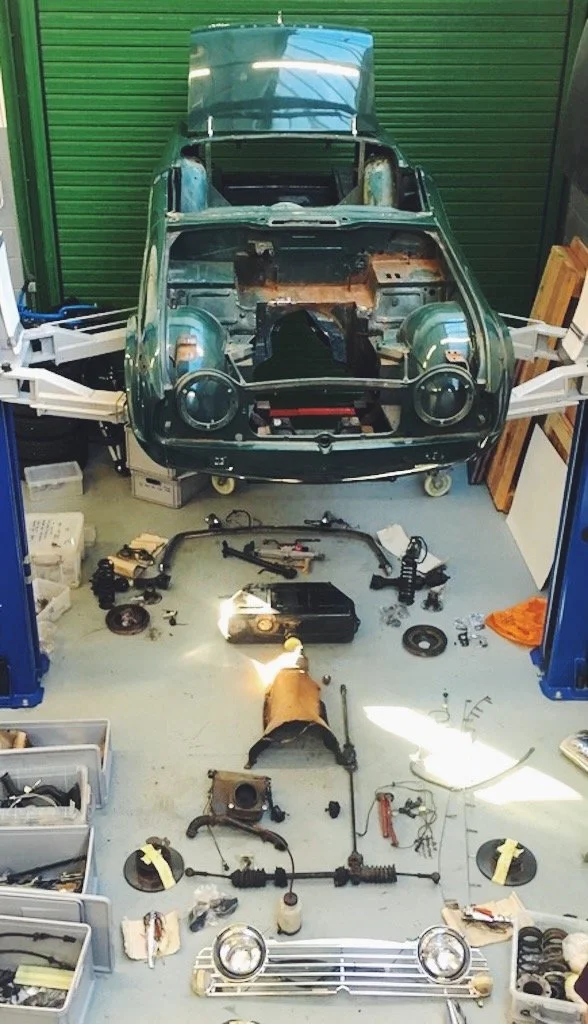 a green classic Triumph TR being reassembled