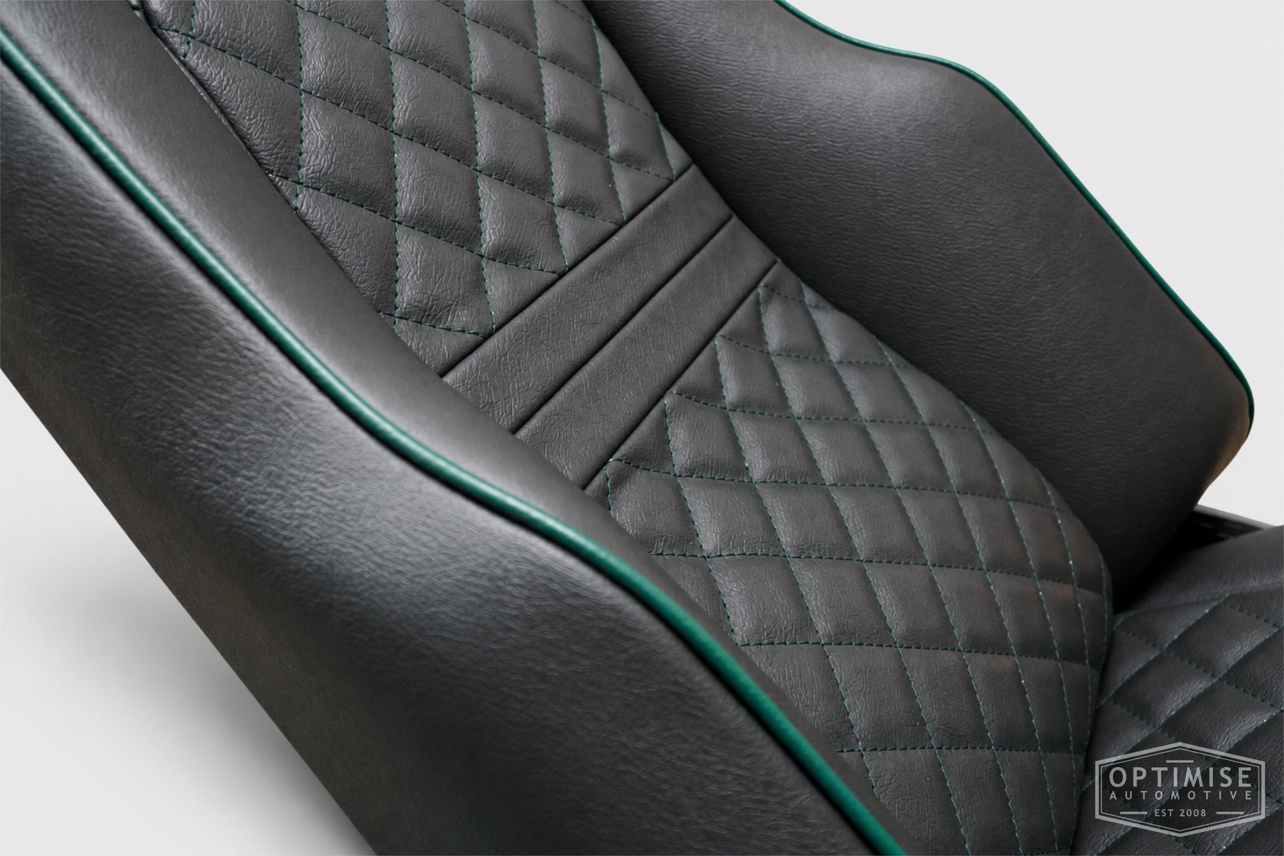 Classic Mini seat retrims featuring Cobra Le Mans front seats and a matching MK5 rear seat, trimmed in black leatherette with British Racing Green diamond stitching and matching green piping.