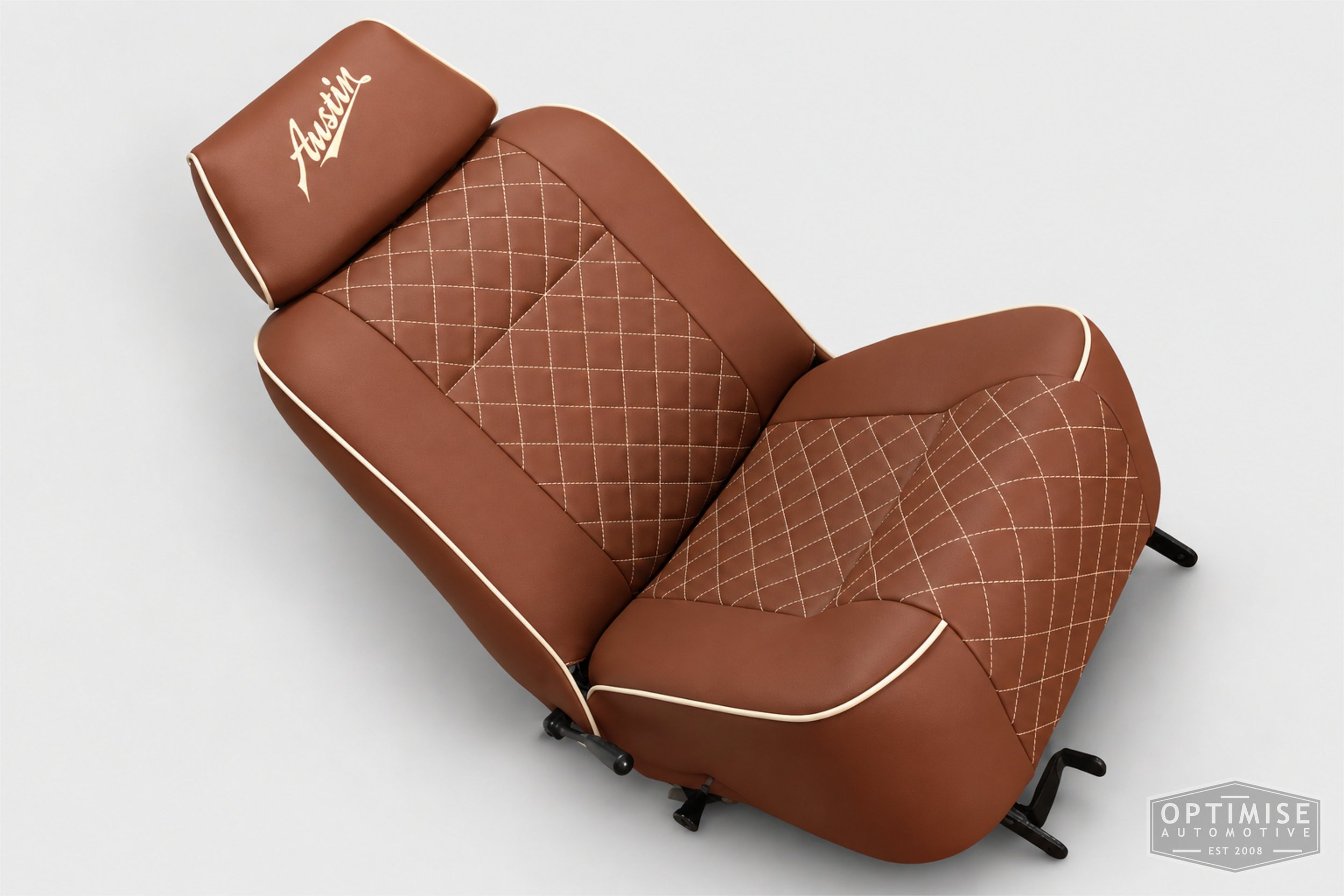 Classic Mini seat retrims featuring original single-post headrest front seats and a matching MK4 rear seat, trimmed in dark tan leatherette with cream diamond stitching and piping, with embroidered headrests.
