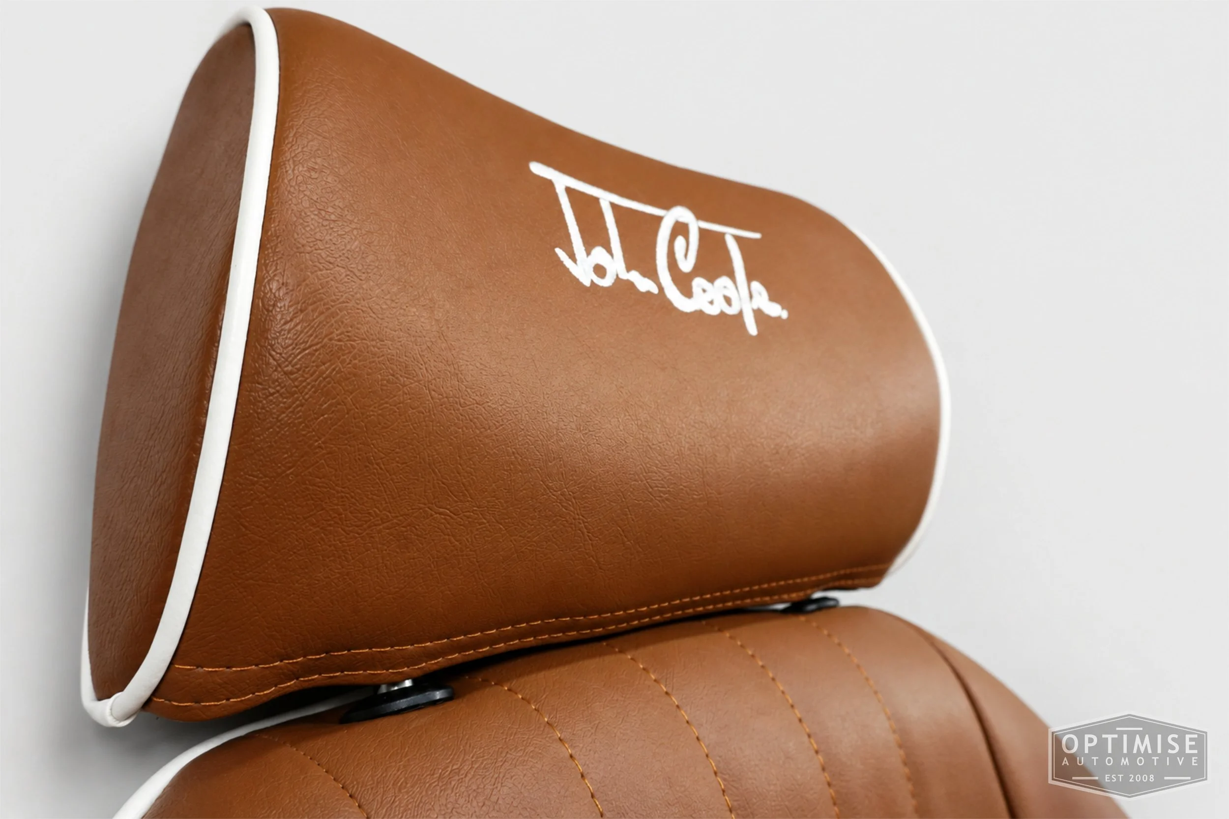 Classic Mini seat retrims featuring Cobra Cub front seats, trimmed in tan leatherette with white piping and John Cooper signature embroidery on the headrests.