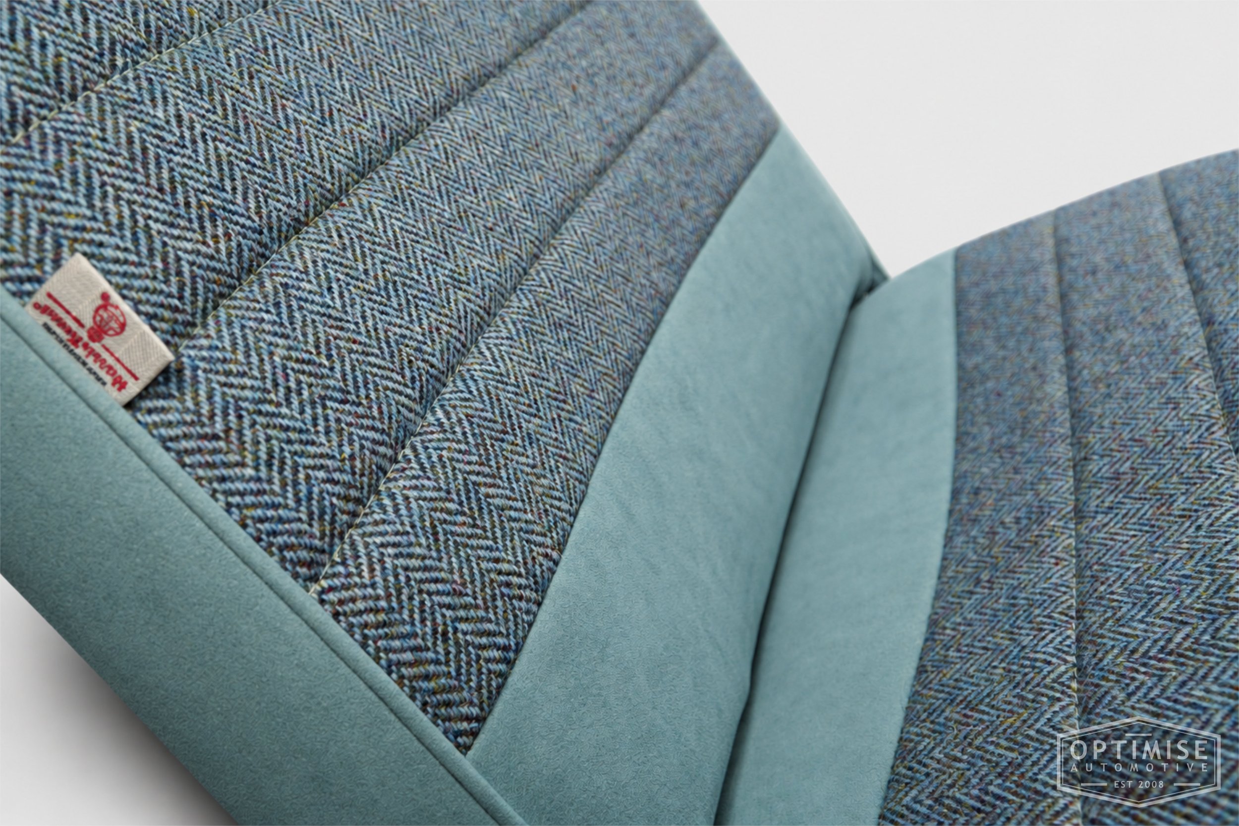 Classic Mini seat retrims featuring original single-post headrest front seats and a matching MK4 rear seat, trimmed in light blue Alcantara and Harris Tweed HB108.