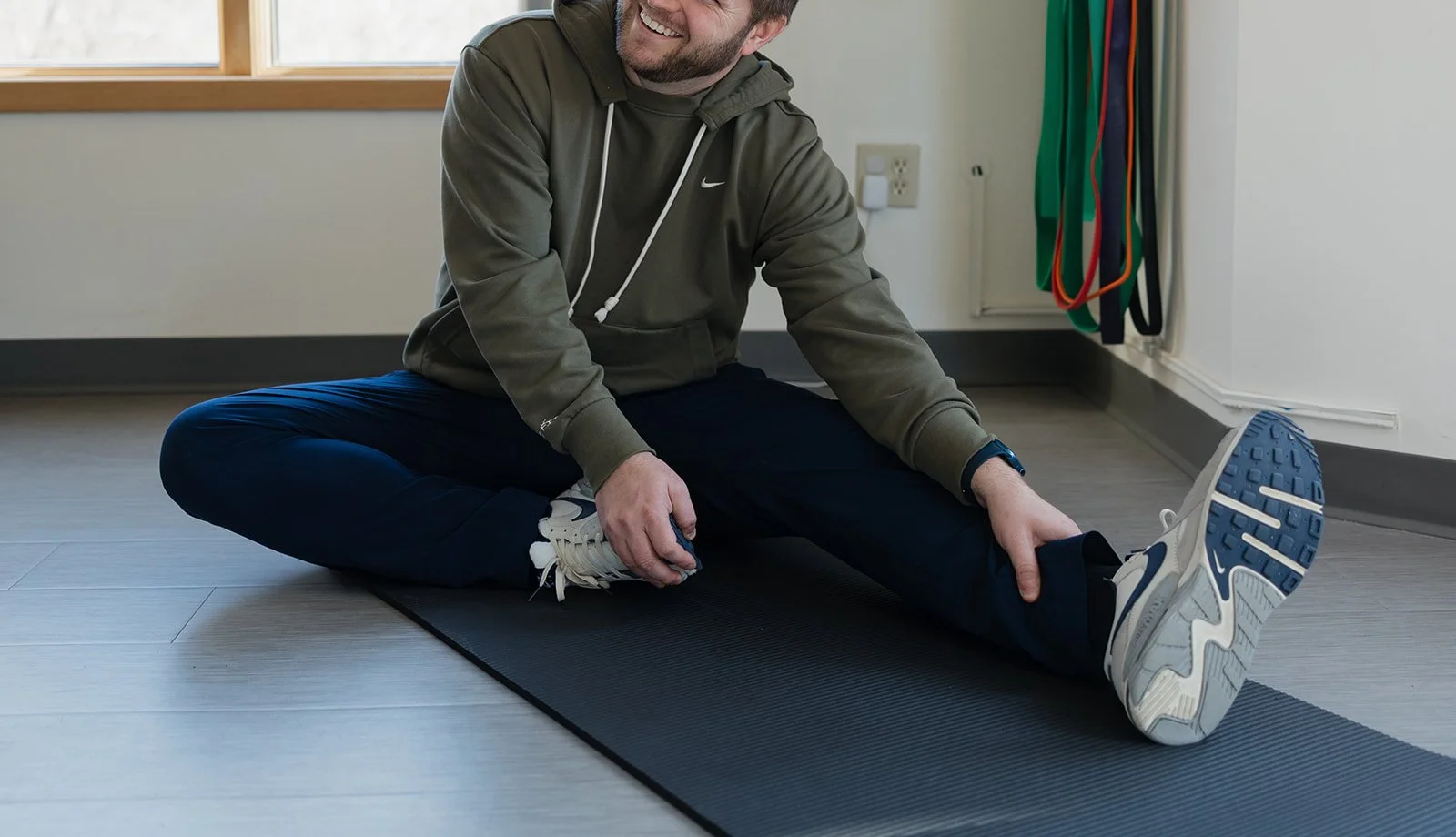 Man smiling while stretching in physical therapy in Columbia, MO