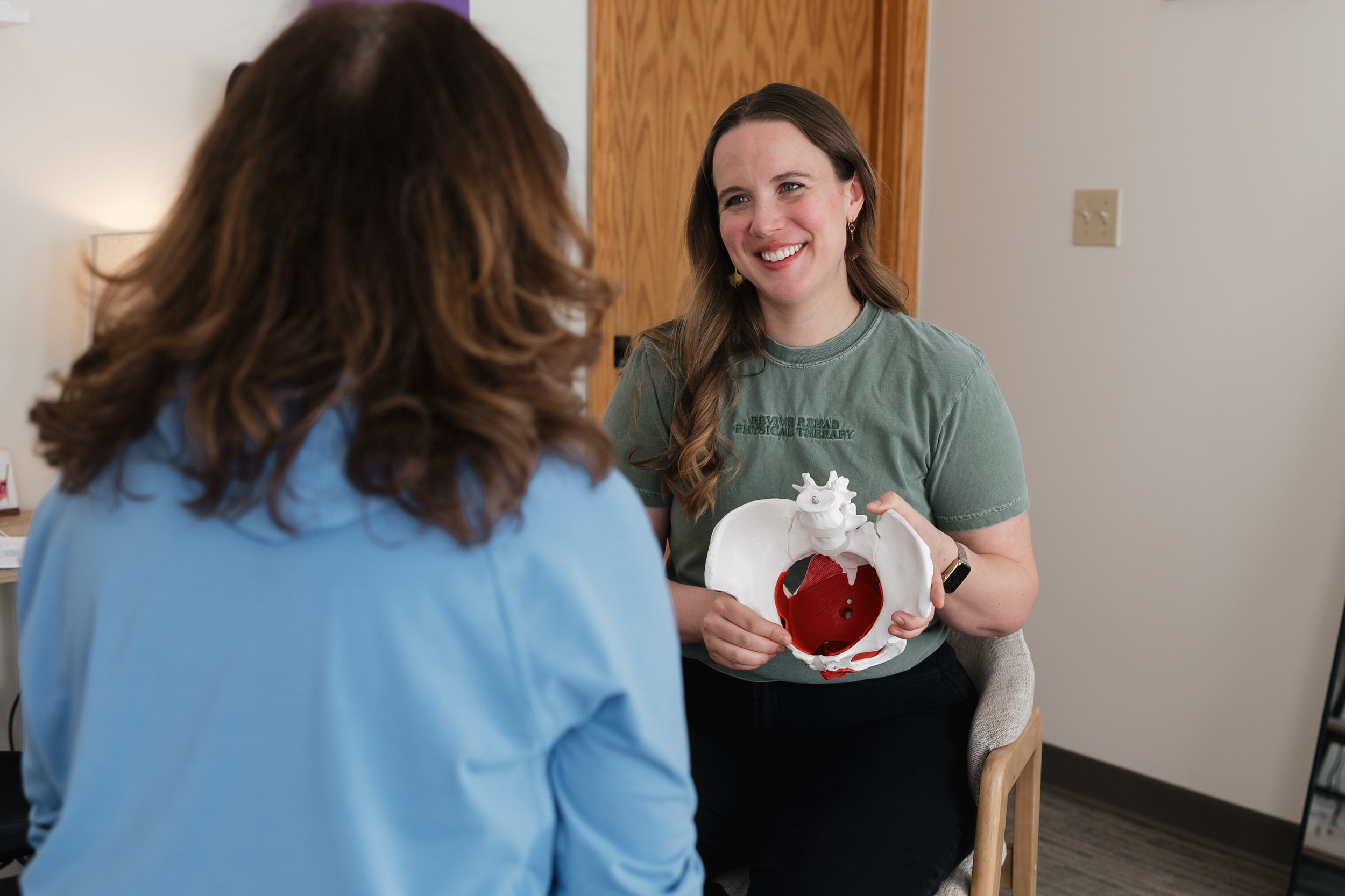 Pelvic floor PT showing a pelvis model to a woman for menopause physical therapy