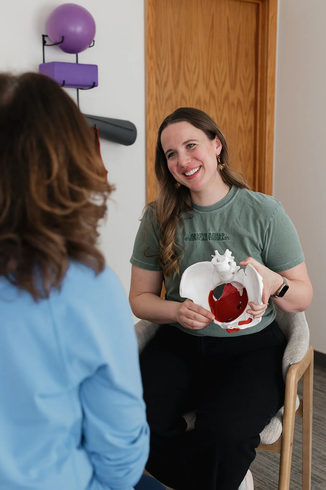 Pelvic health therapist educating on pelvic floor PT to postpartum woman in physical therapy clinic in Columbia, MO