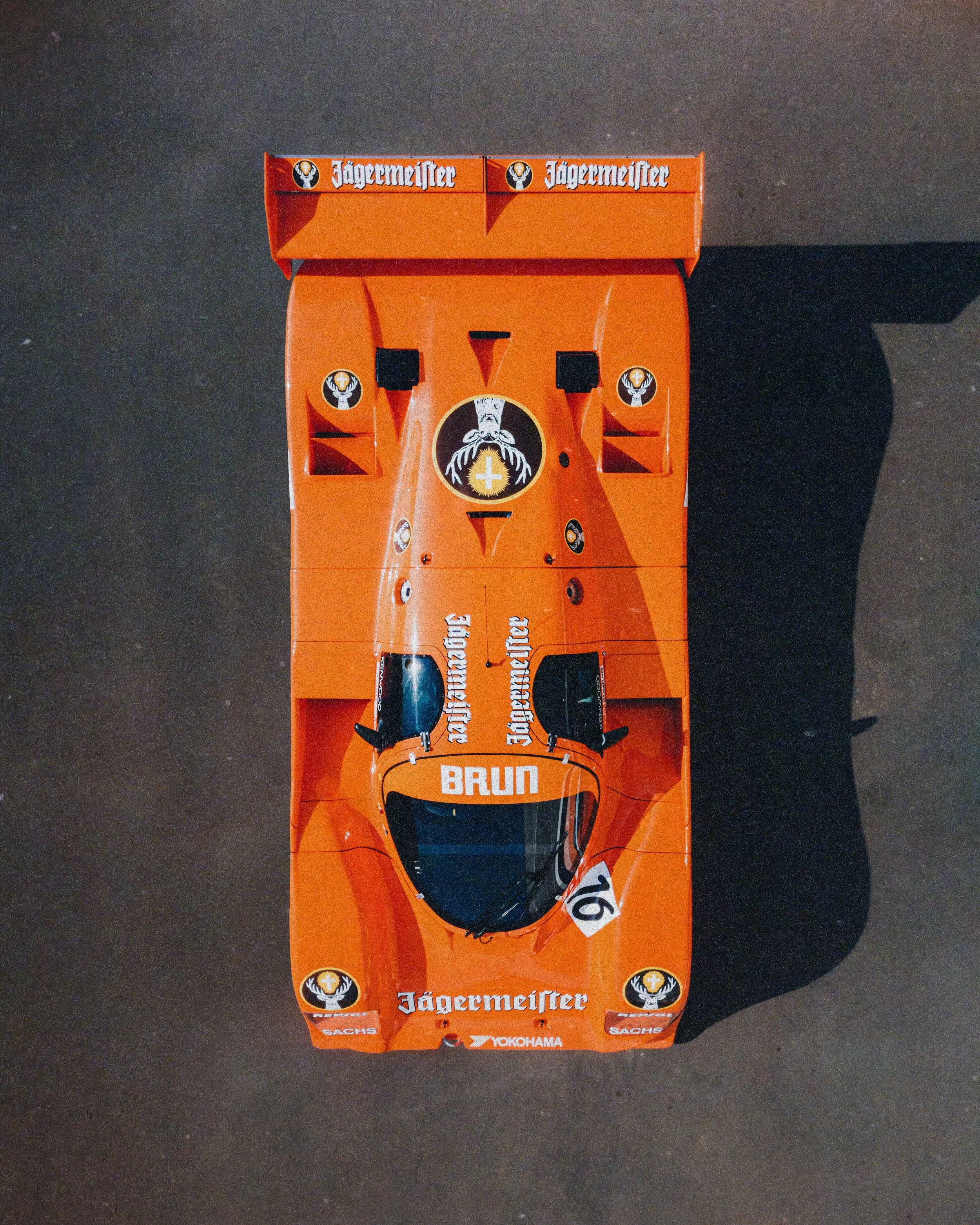 Top view of a vintage orange Jägermeister racing car with sponsor logos and racing number 16.
