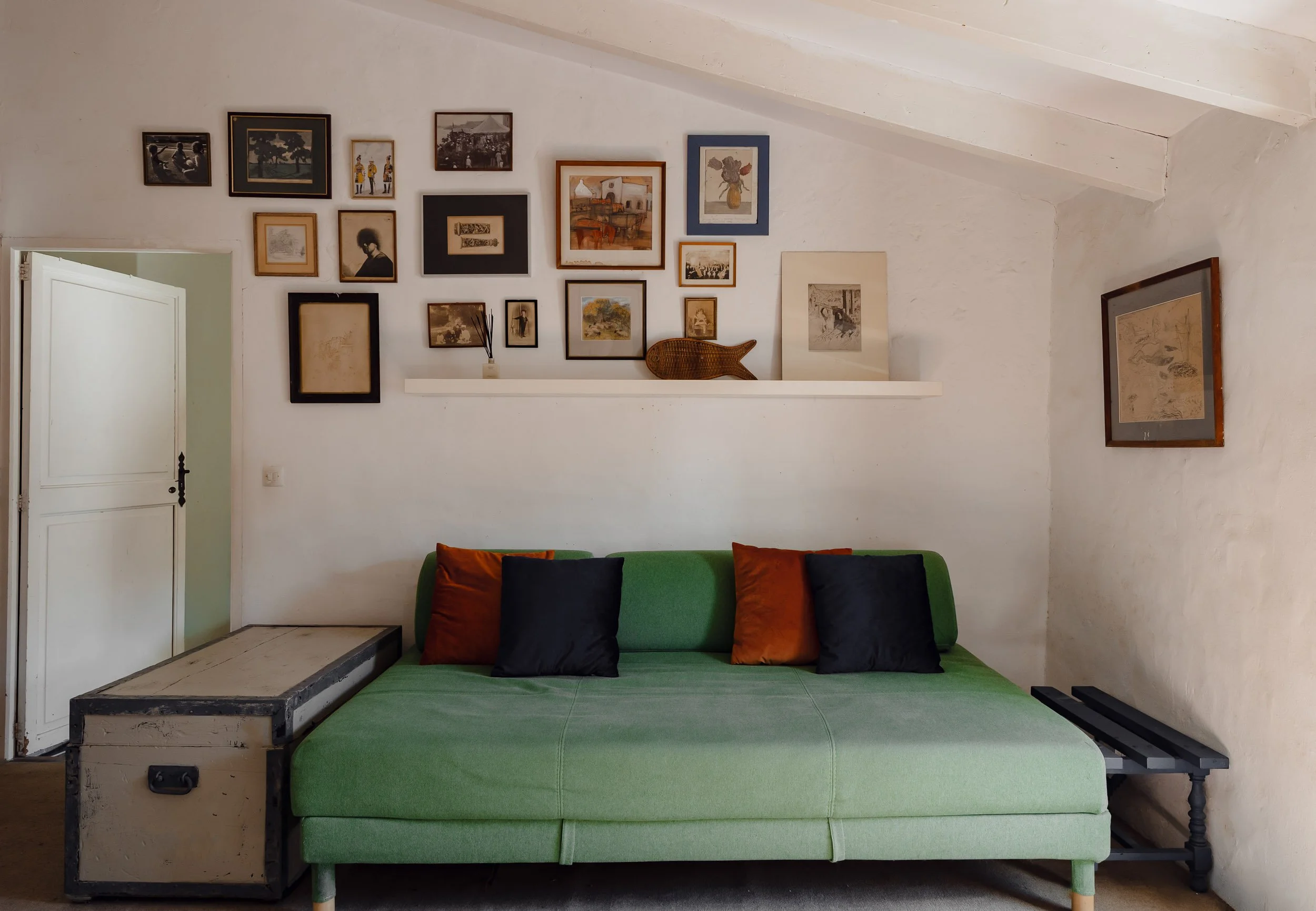 Curated art gallery wall with vintage sketches positioned above a minimalist green daybed.