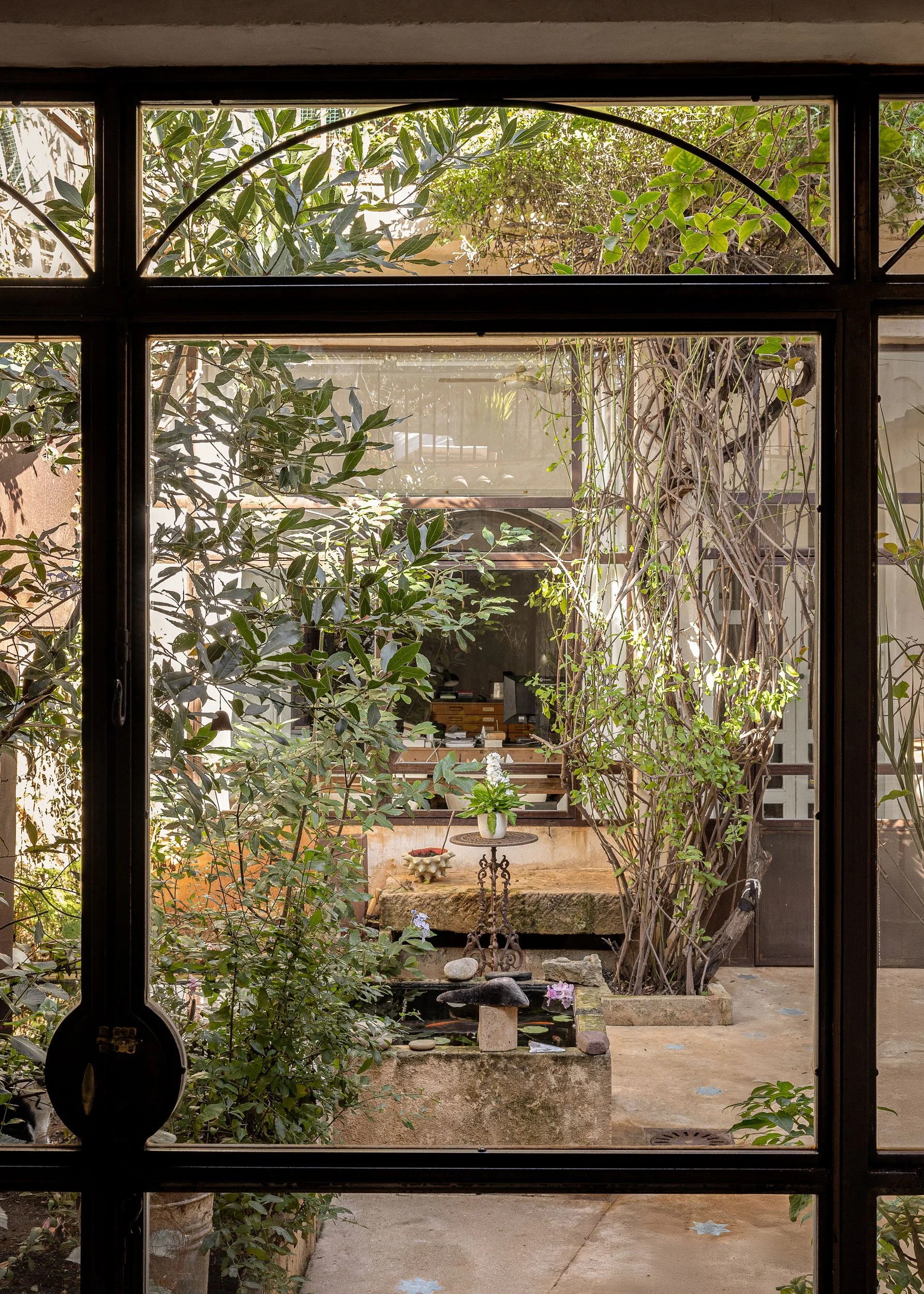 View through glass doors into a lush Mediterranean courtyard