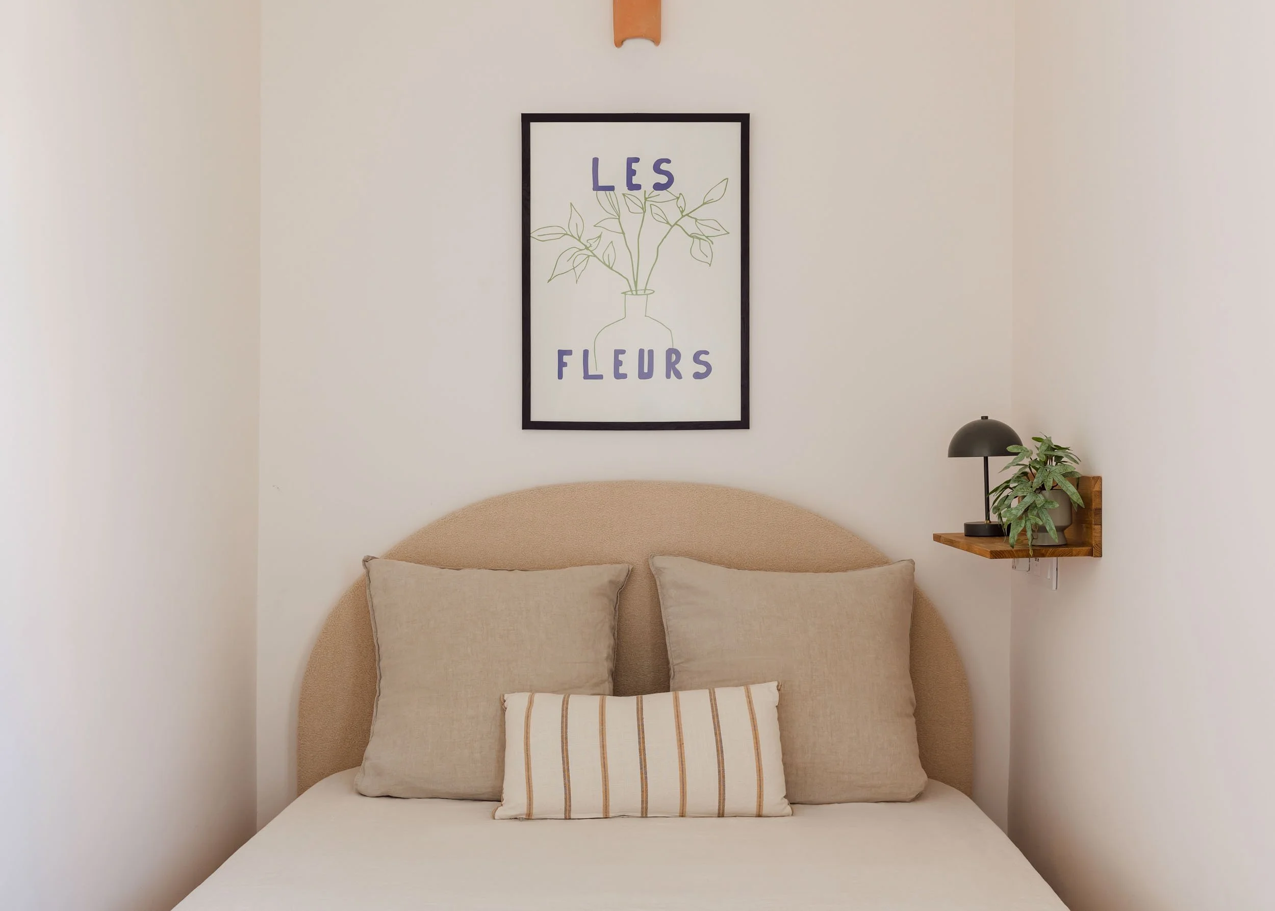 Bed detail with textured headboard and framed wall art