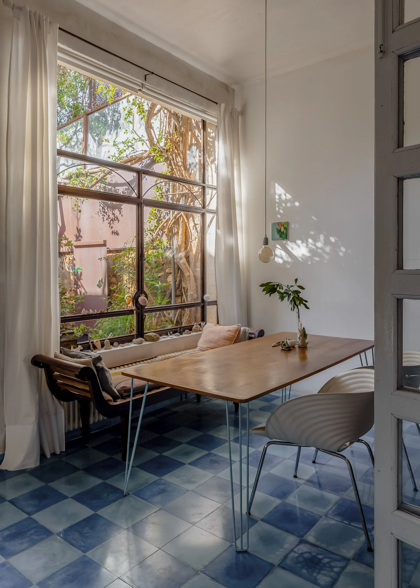 Dining nook with wooden table, blue tiles, and garden views