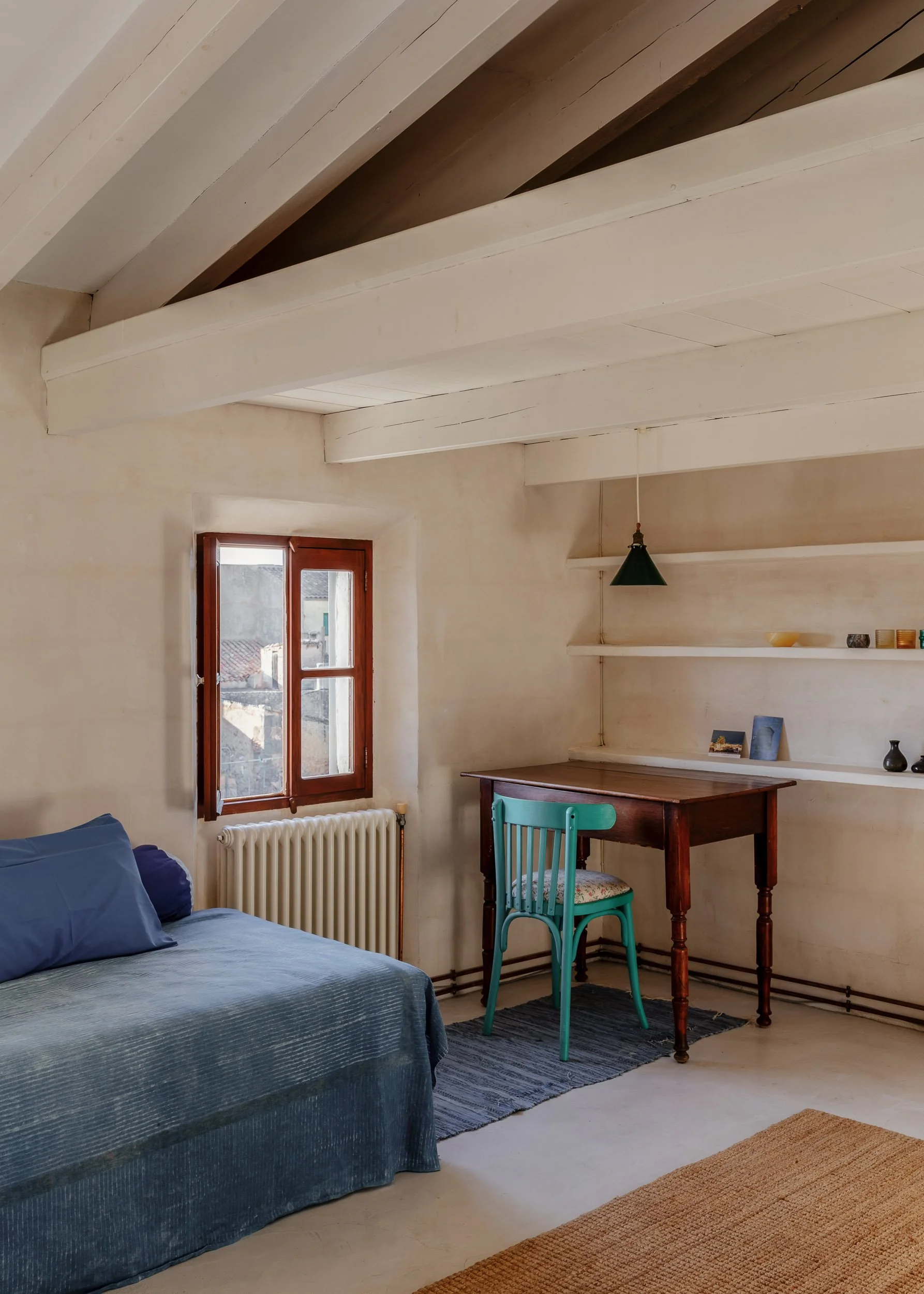 Minimal bedroom with exposed beams and simple wooden desk