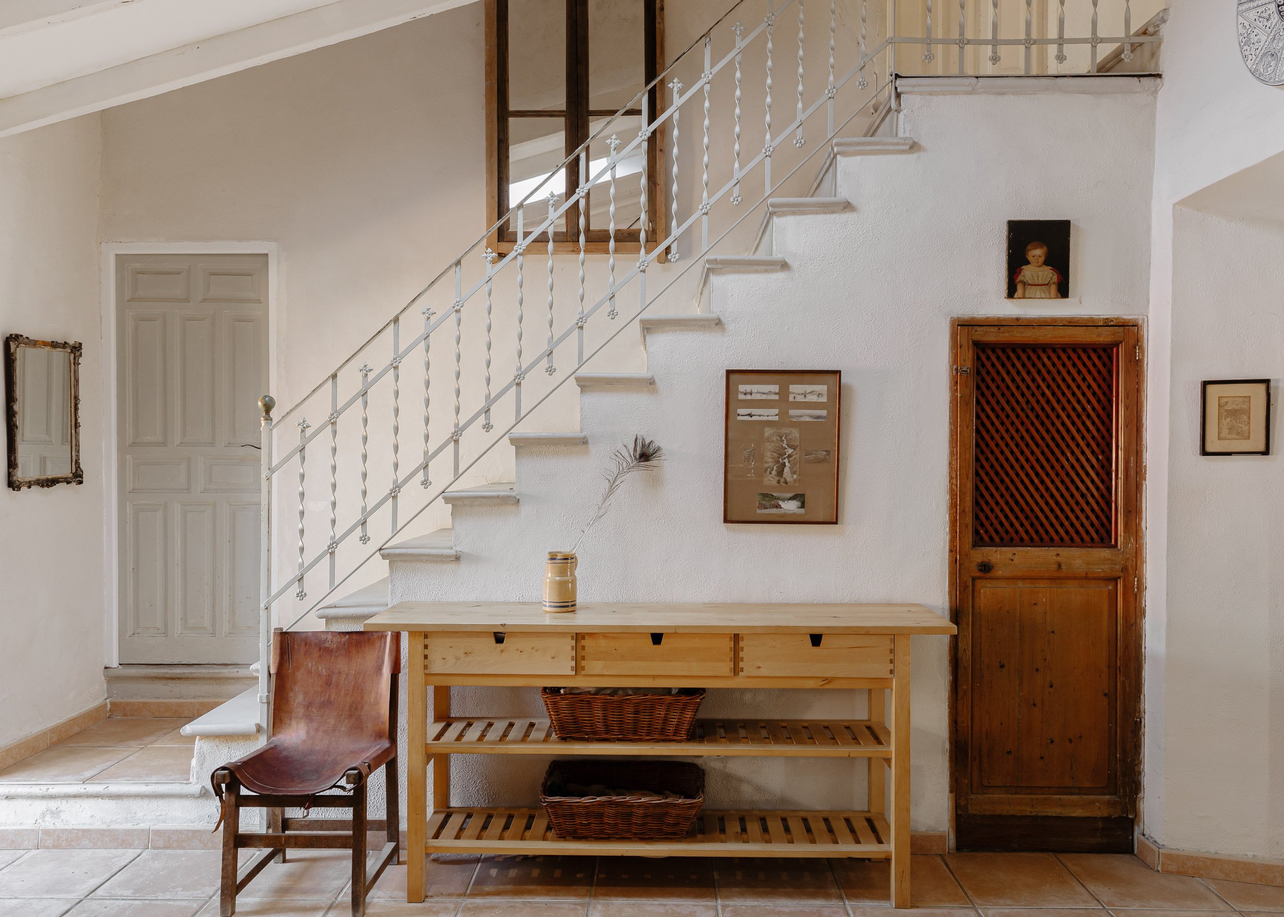 Bright, airy entryway featuring a white washed staircase and traditional wooden furnishings.