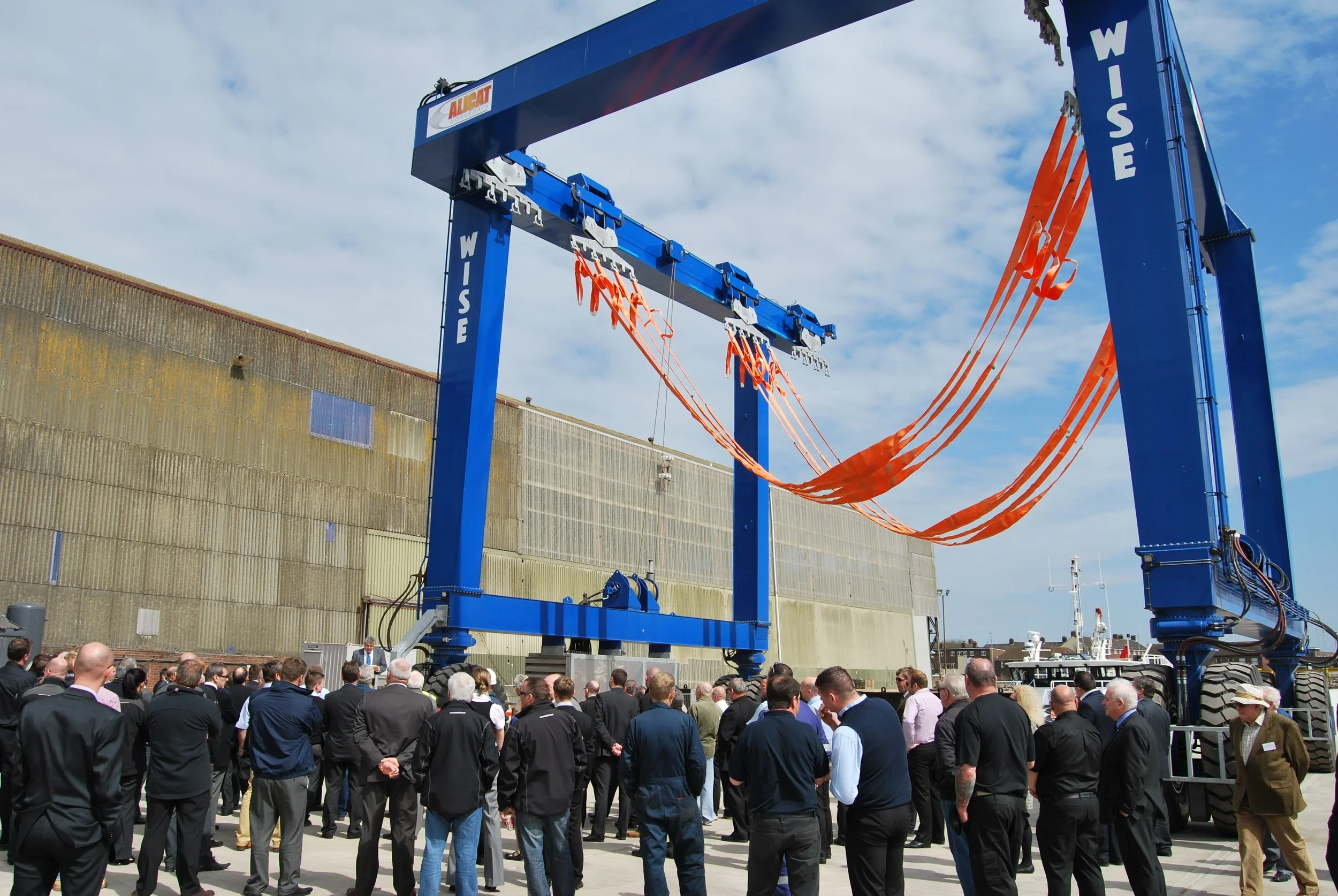 A large blue WISE boat hoist in a dock yard