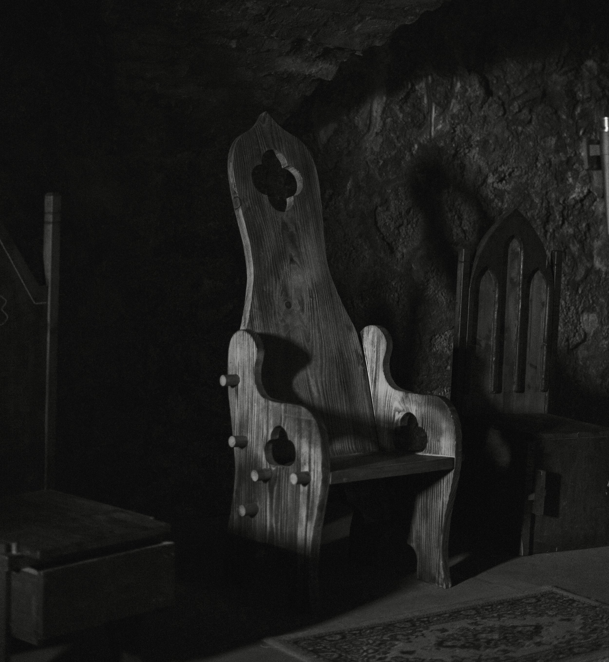 gothic Wooden benches arranged in an indoor space with a dark, textured wall behind them. used in place of a tattoo bed to give the page a more gothic and occult witchy feel