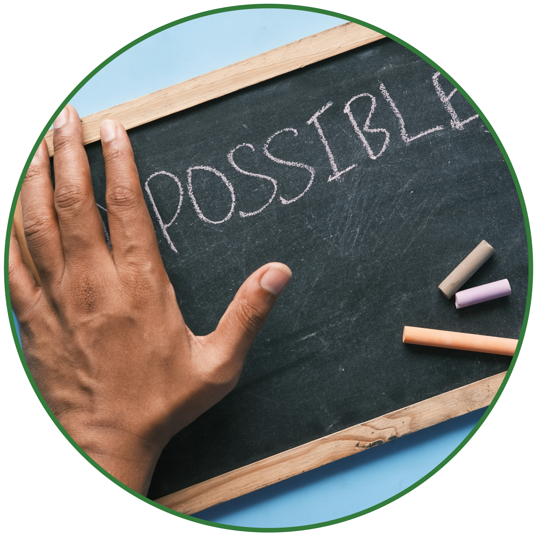 Hand writing the word 'POSSIBLE' on a black chalkboard with white chalk, with pastel chalks on the side.