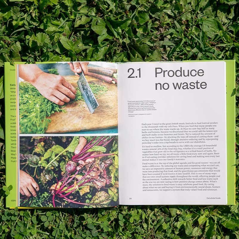 The cover of the book Eating for Pleasure, People & Planet lies open to the 'produce no waste' pages against brightly lit grass.