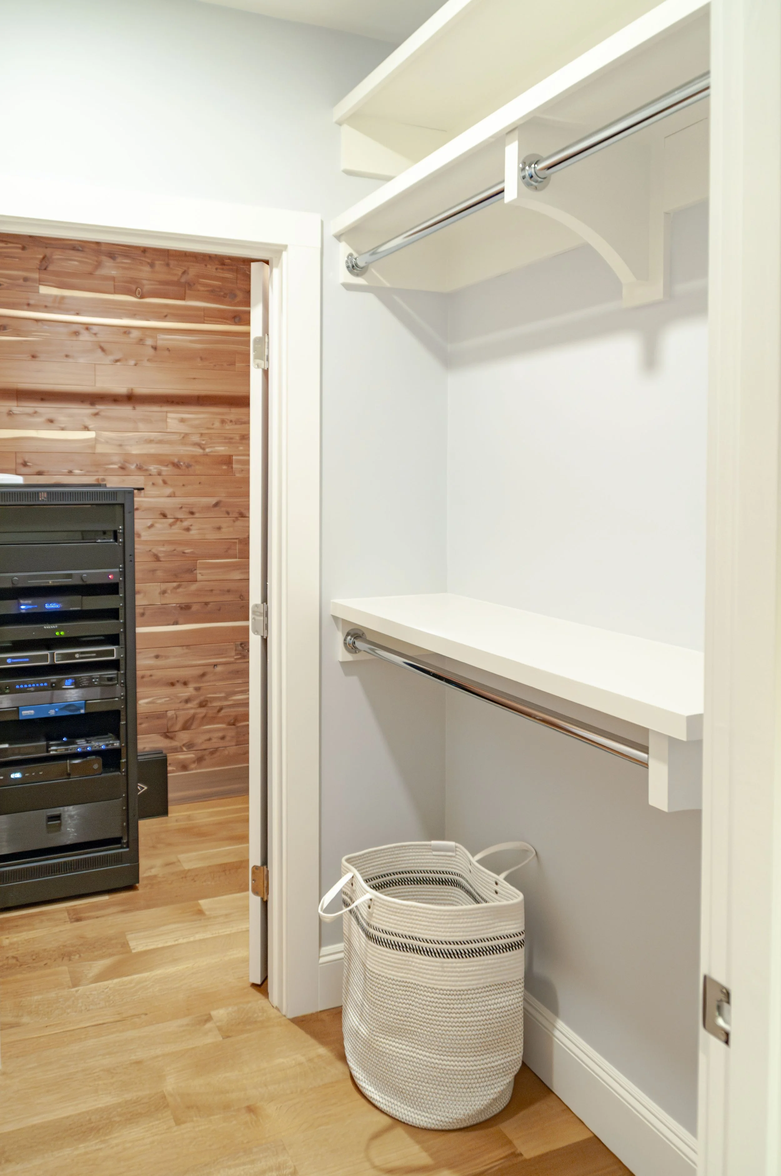 Cape Cod closet with white shelving, chrome hanging rods, and cedar-lined room beyond.