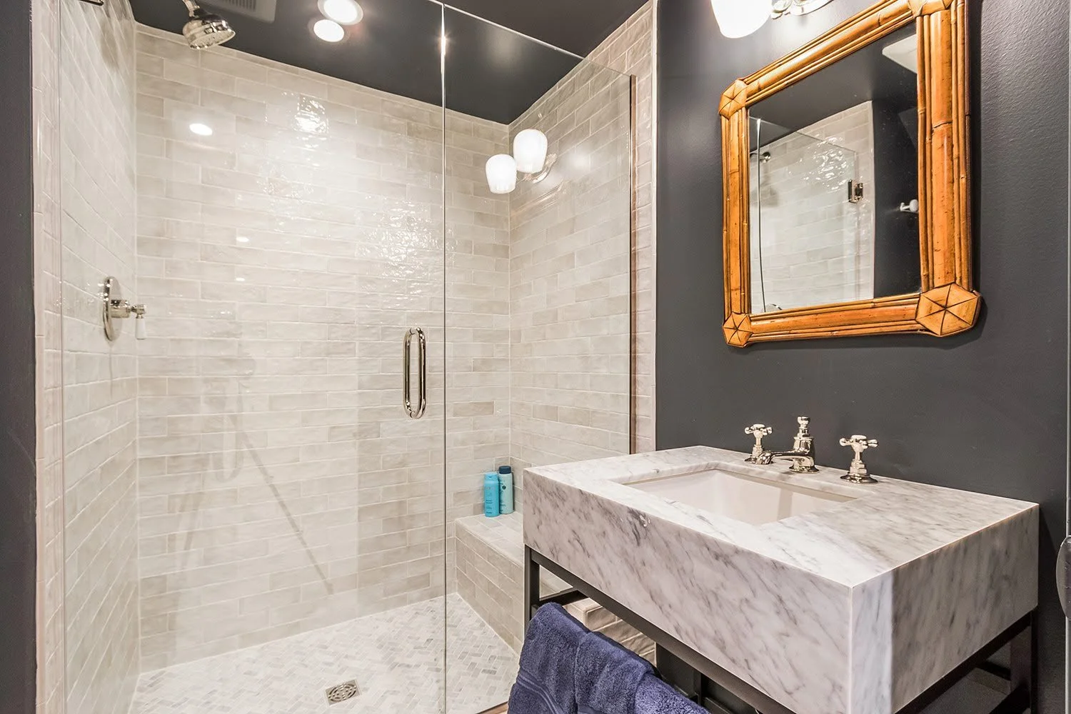 Marble finishes and a glass shower bring high-end Cape Cod renovation detail to this compact bathroom.