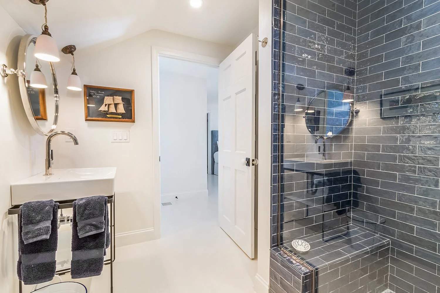 A luxury home builder in Osterville bath showcases glossy blue tile, glass shower, and a compact white vanity