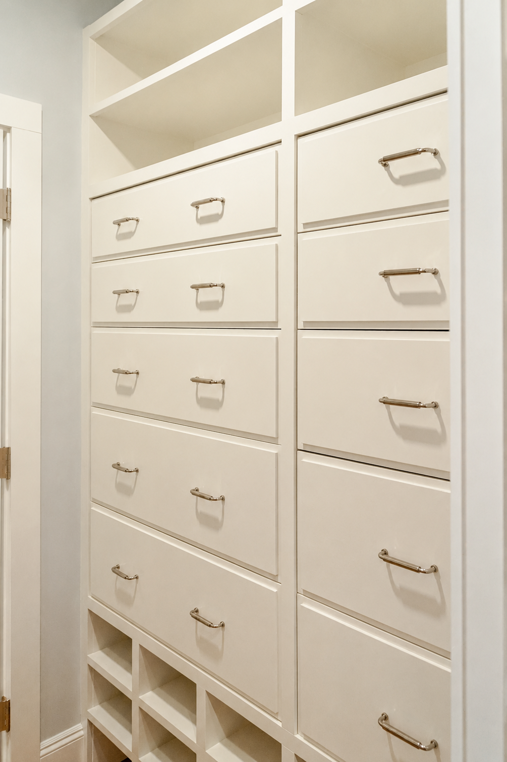 Floor-to-ceiling custom cabinetry provides organized drawer storage, open display shelves, and tailored built-ins that maximize space in this Cape Cod custom home.