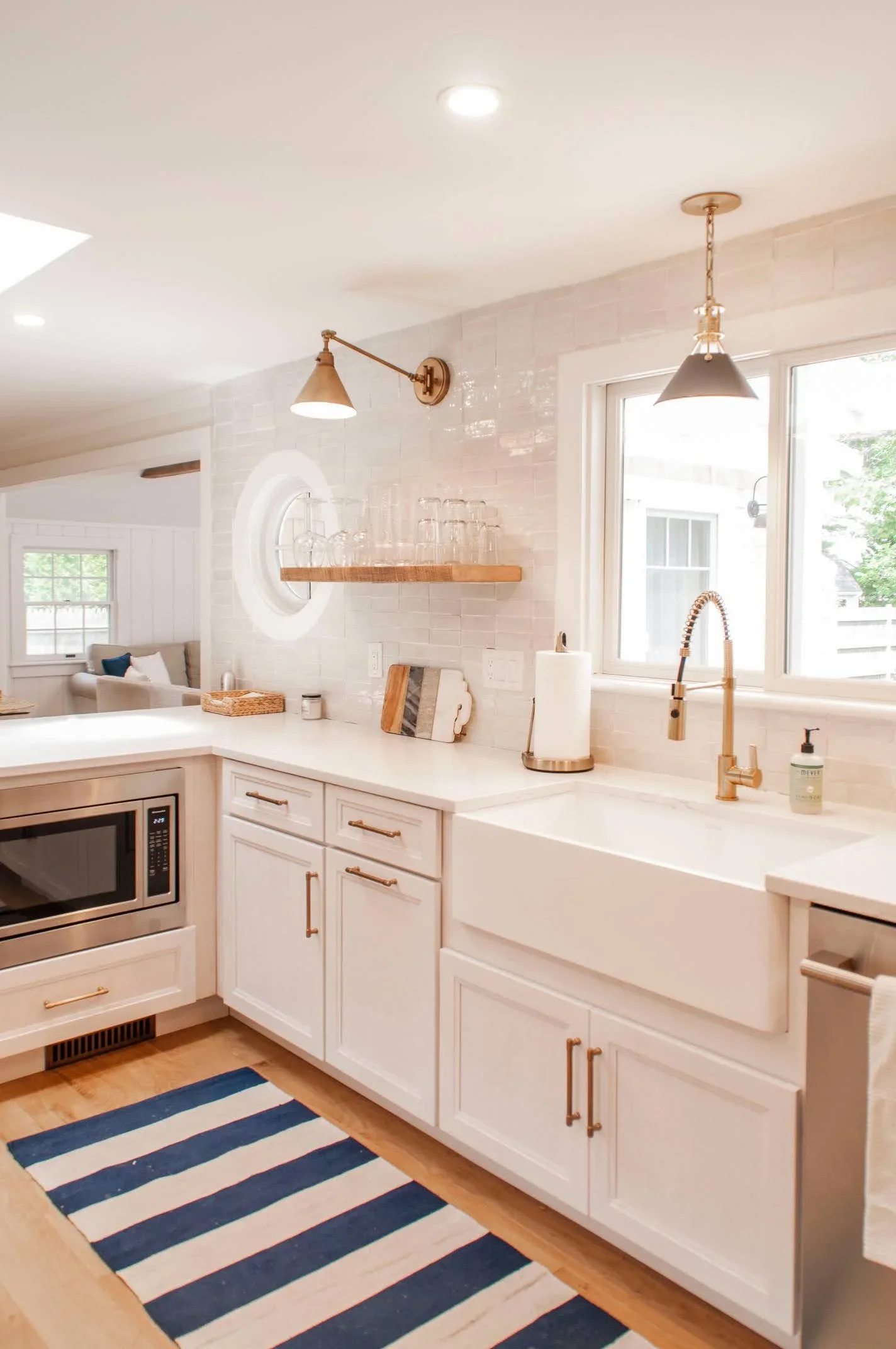 Sea View Builders designed this custom Cape Cod kitchen with a farmhouse sink, quartz countertops, brass hardware, and bright coastal-inspired finishes.