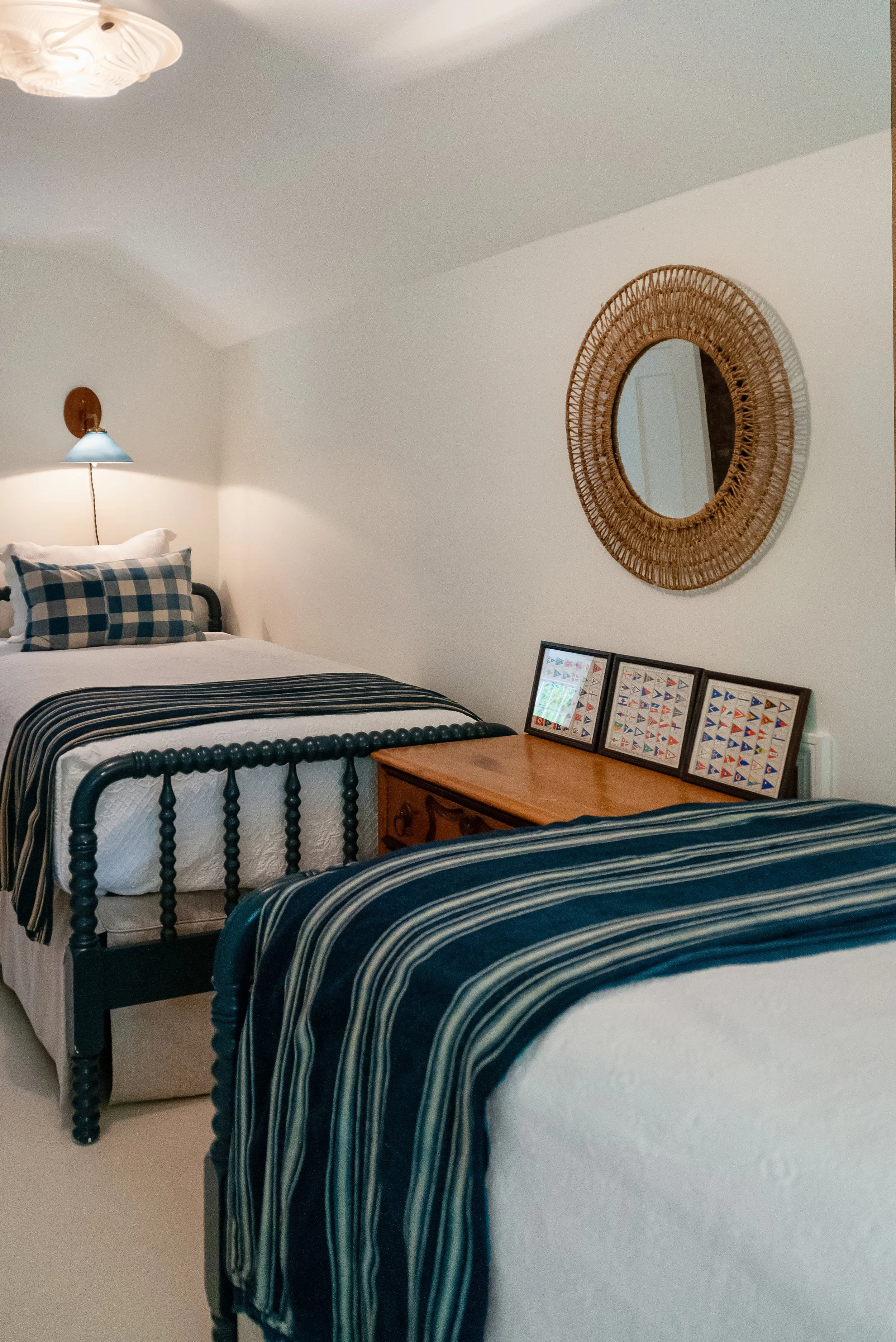 Coastal guest bedroom in a custom Cape Cod home with twin beds, navy accents, and framed sailboat art.