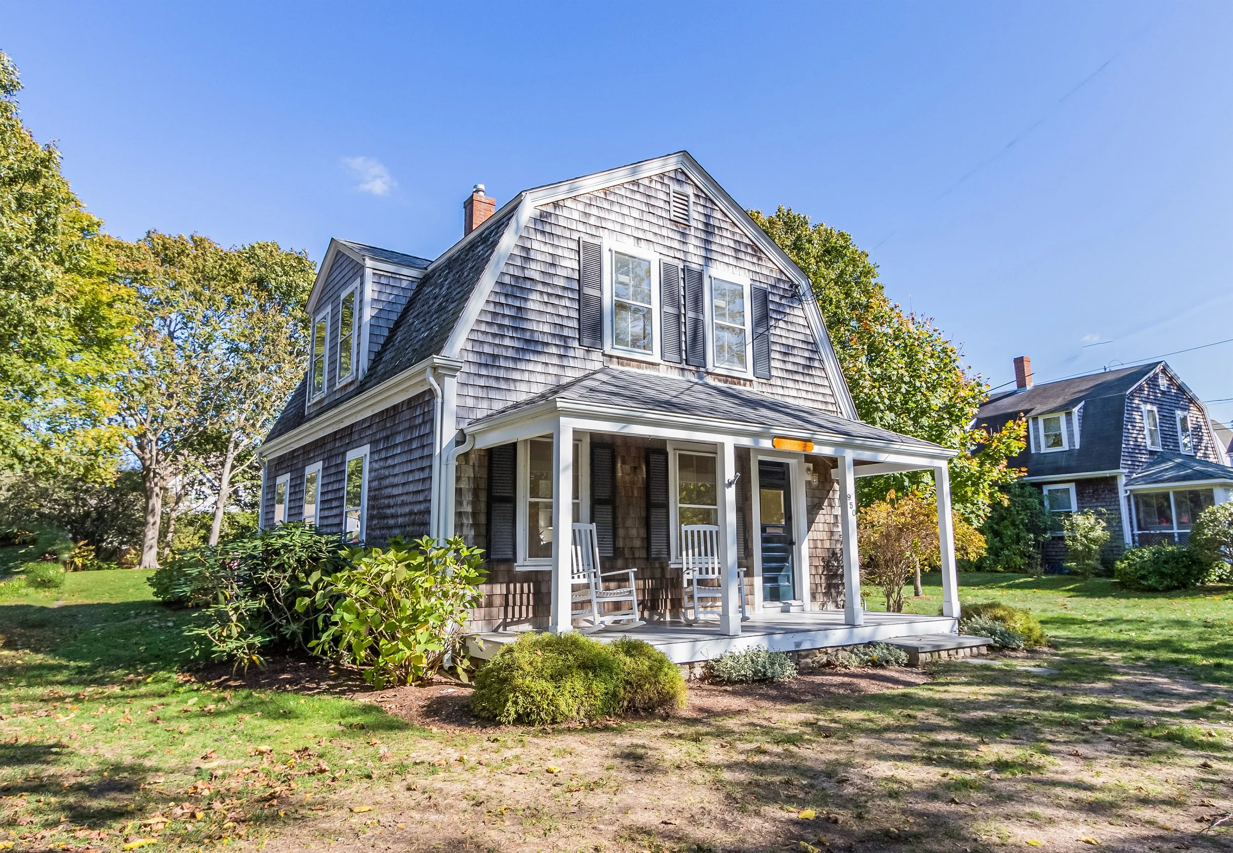 Weathered shingle cottage with front porch, rocking chairs, and classic Cape Cod curb appeal.