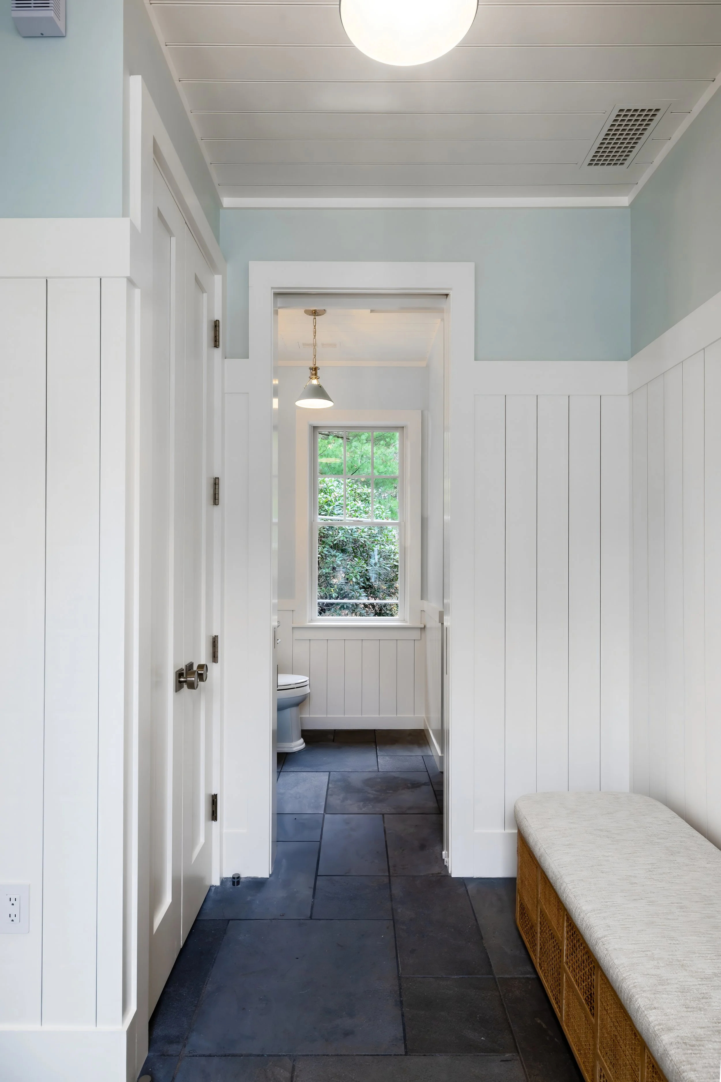 Pool House entry with white paneling, blue walls, slate flooring, and built-in bench. 