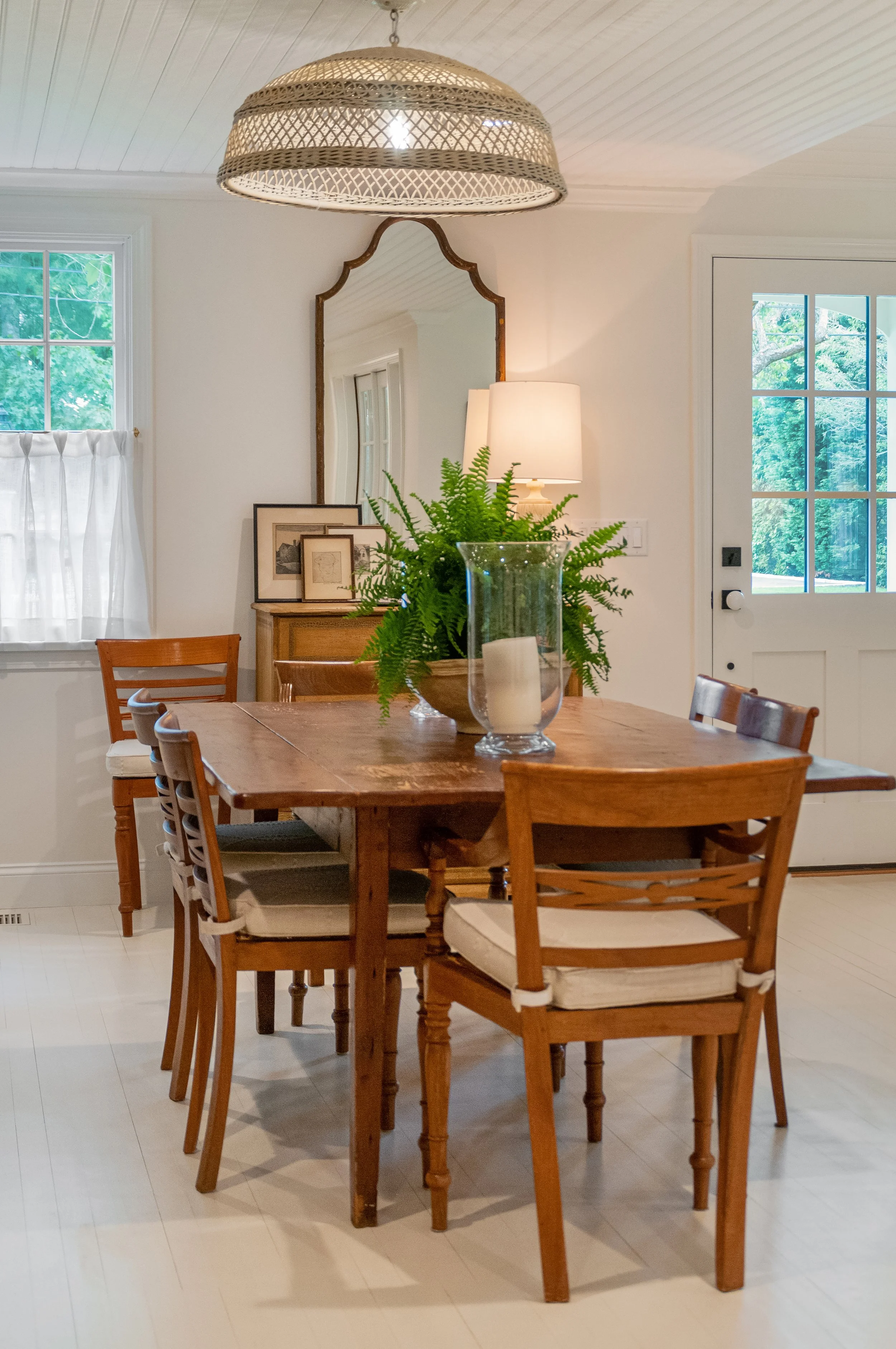 Wood dining table, woven pendant, and beadboard ceiling define this coastal dining room design.