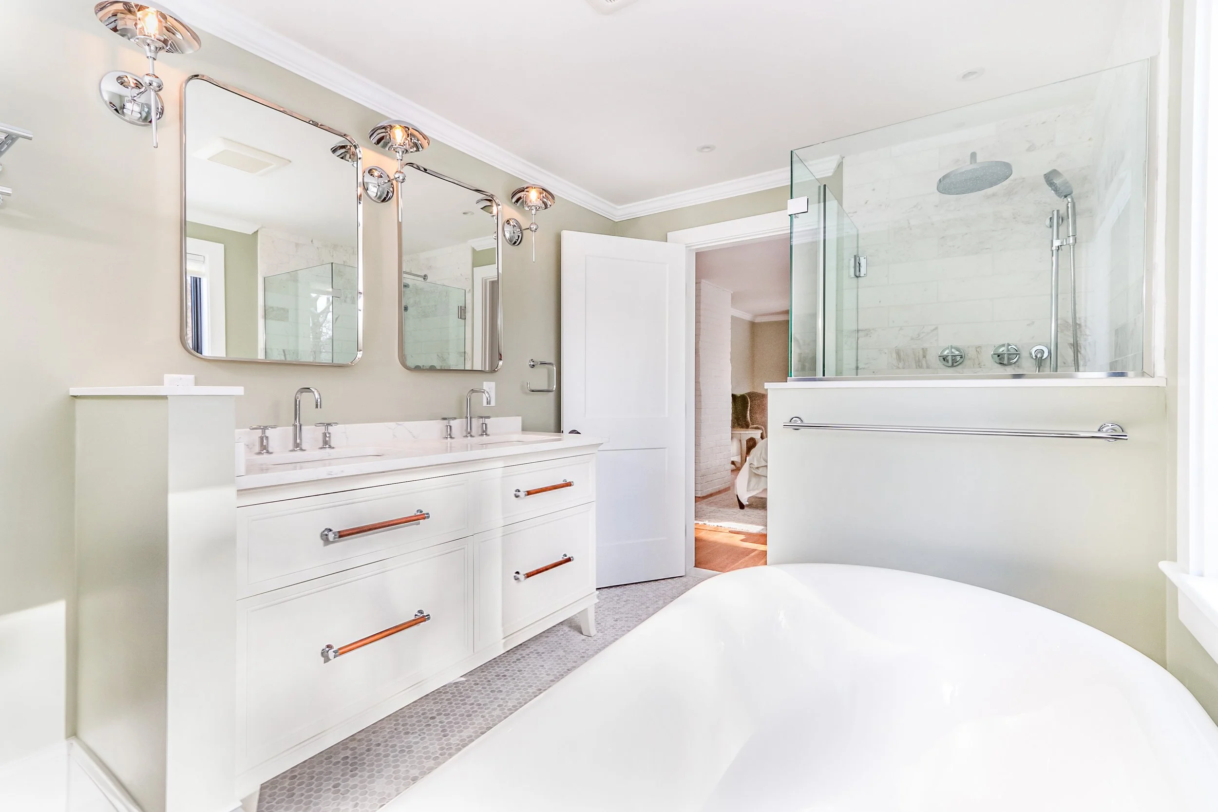 This custom coastal home bath features a freestanding tub, glass shower, double vanity, and polished chrome fixtures.
