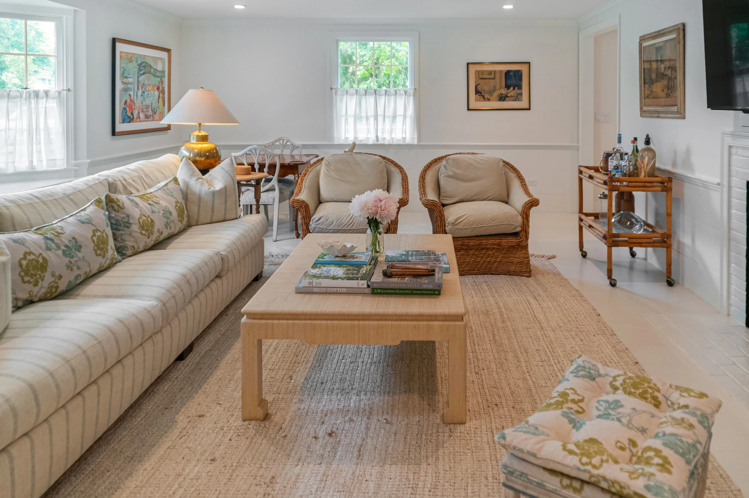 Wicker seating and layered textiles bring coastal family room design to this bright Cape Cod interior.