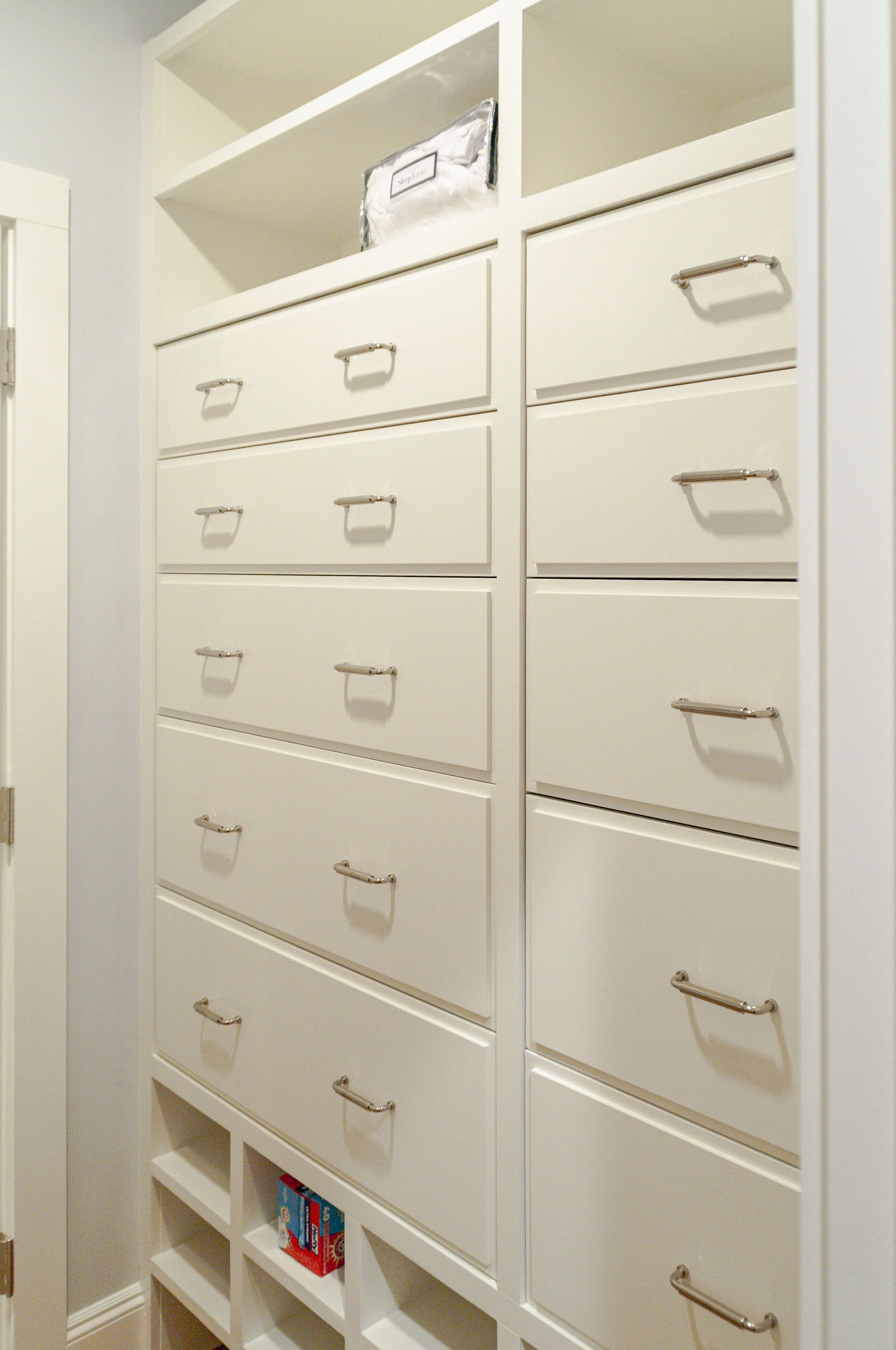 Cape Cod closet detail with built-in drawers, open cubbies, polished pulls, and white millwork.