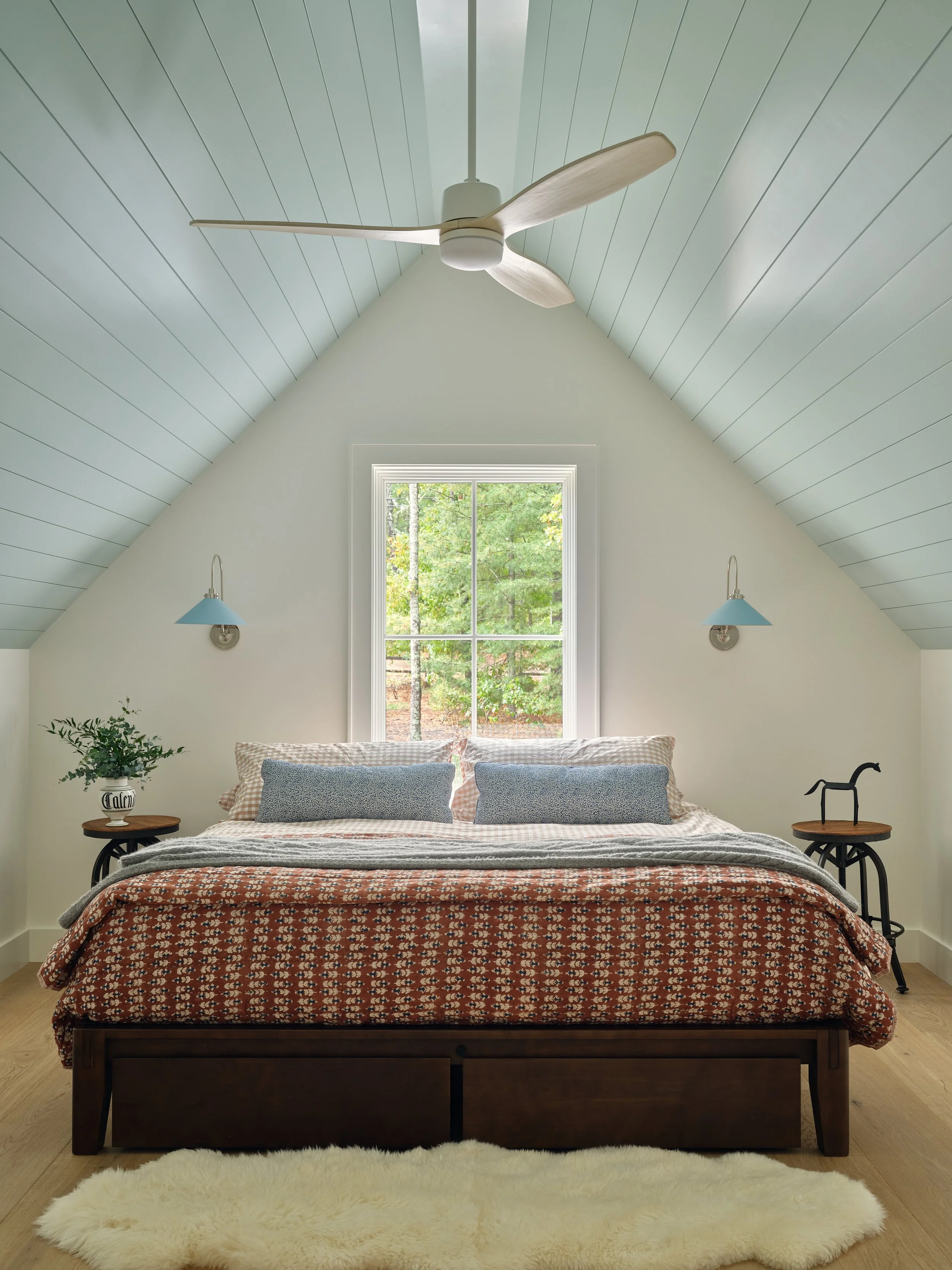 Centered beneath vaulted ceilings, this Sea View Builders bedroom features painted shiplap, oversized windows, and timeless Cape Cod coastal design.