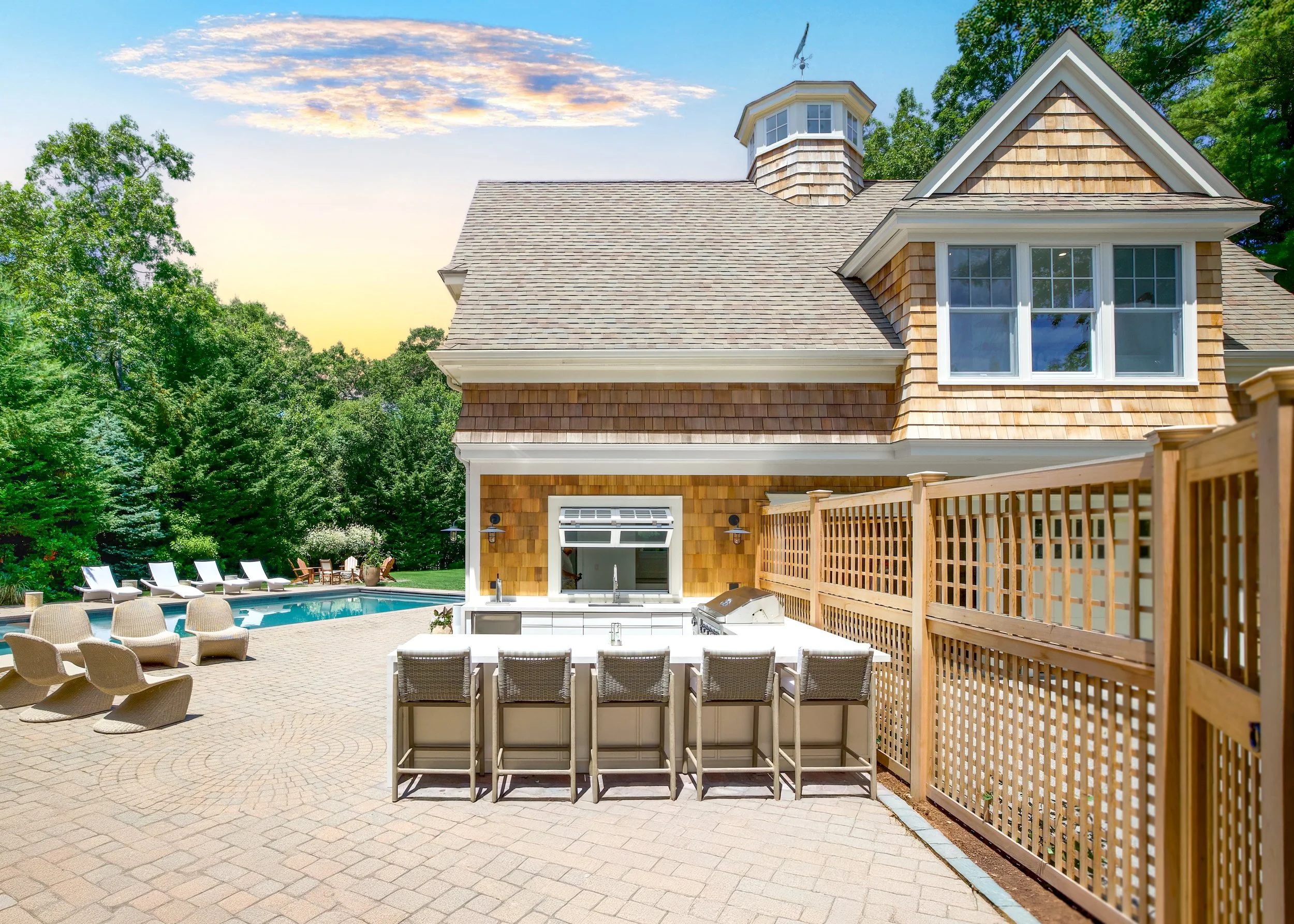 Outdoor bar seating, cedar privacy lattice, and poolside patio create polished Cape Cod backyard entertaining.