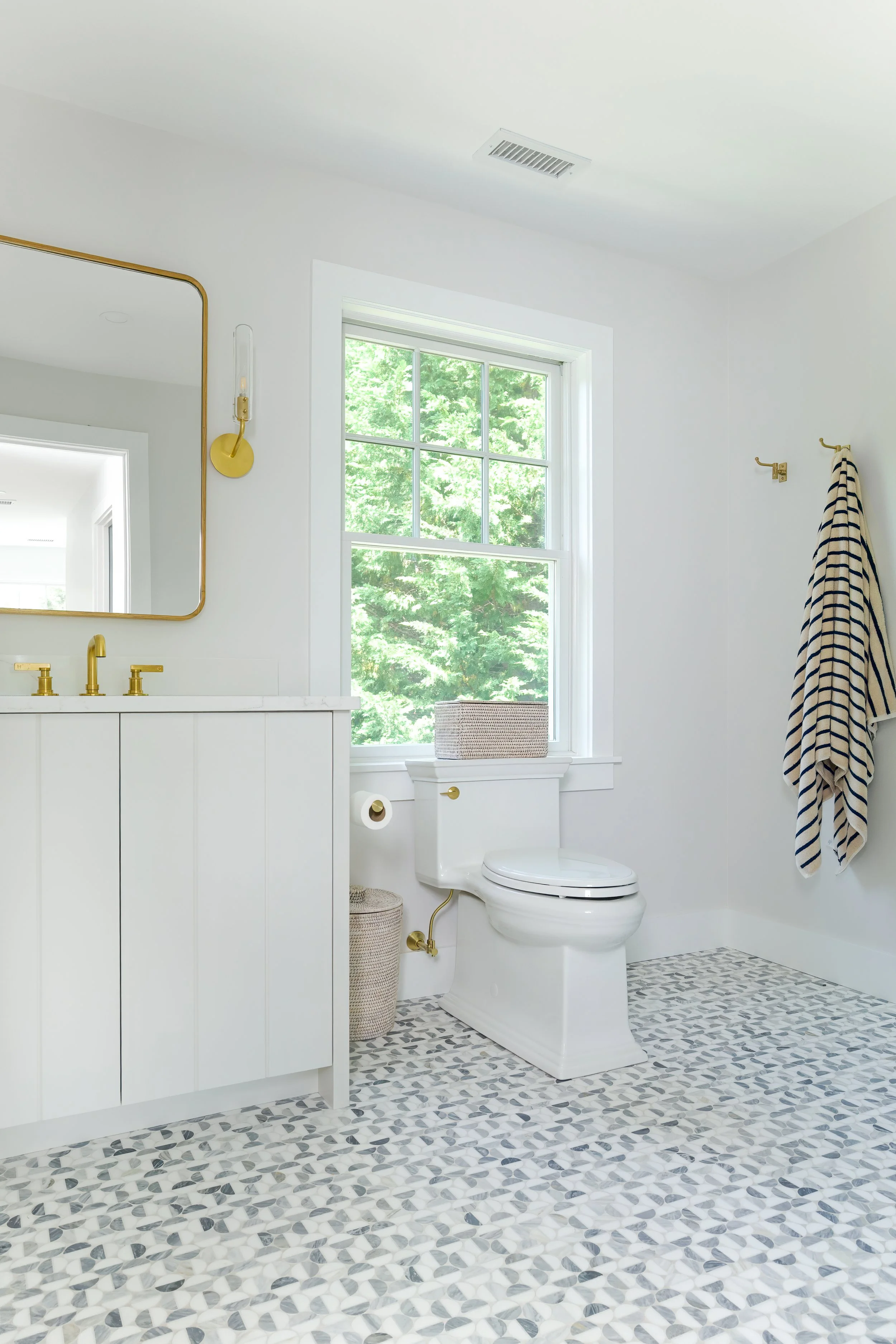 Custom Osterville bathroom with a spacious glass shower, premium brass fixtures, while tile surround, decorative mosaic flooring, and luxury Cape Cod home interior design.
