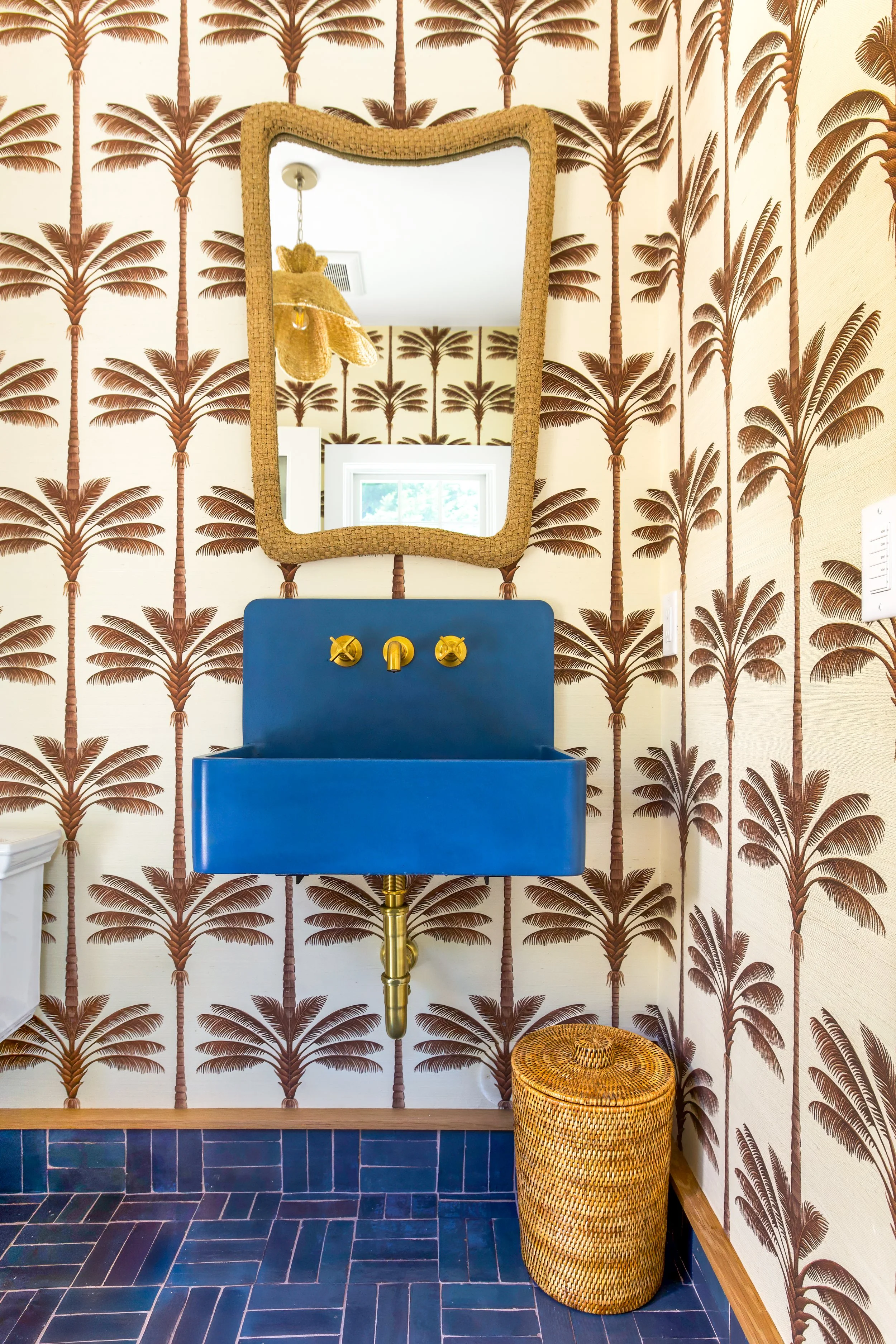 Custom Osterville bathroom with statement palm wallpaper, blue vessel sink, brass fixtures, decorative mirror, and luxury Cape Cod interior design.