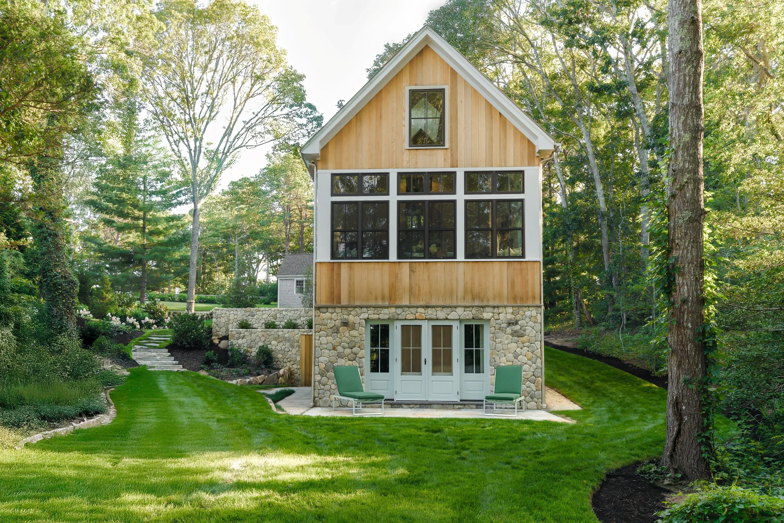 Custom Coastal Home with expansive windows, lower level doors, and a lush Cape Cod Lawn.