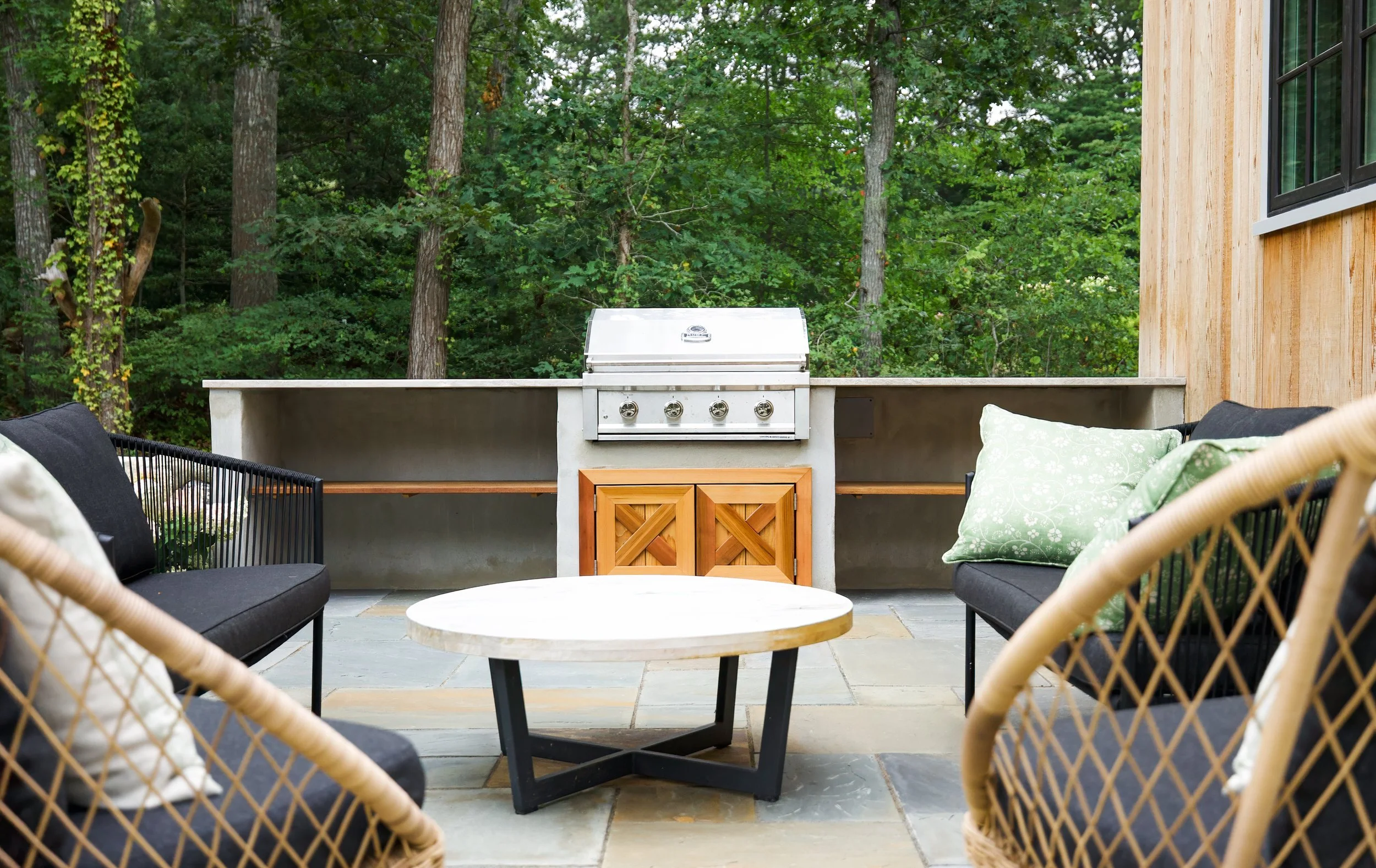 Centered around a built-in grill, this Sea View Builders outdoor living space features a custom grilling station, bluestone patio, and Cape Cod backyard entertaining area.