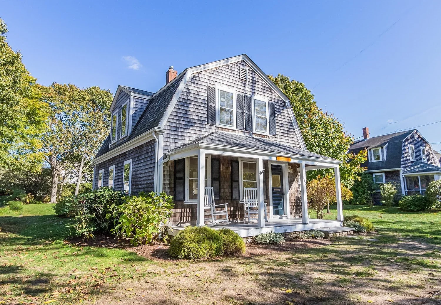 Classic Cape Cod home with cedar shingles, a covered front porch, and traditional coastal architecture by Sea View Builders.