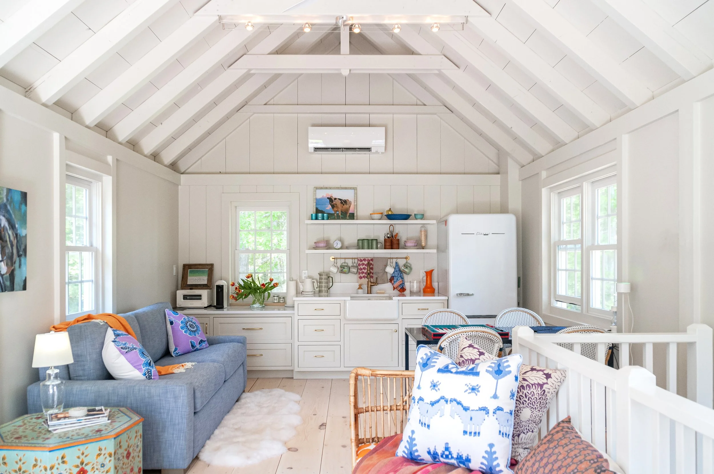 Vaulted ceilings and colorful furnishings define this custom coastal home living space with kitchenette and dining area.