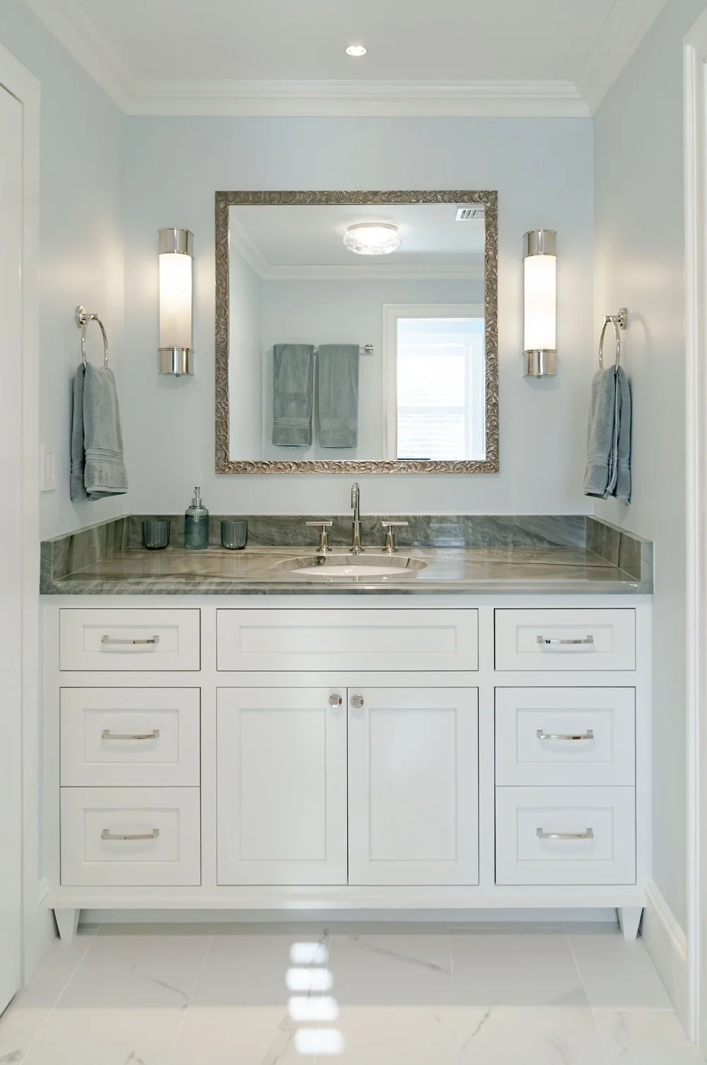 White vanity cabinetry and green stone counters bring custom coastal home detail to this bright Cape Cod bath.