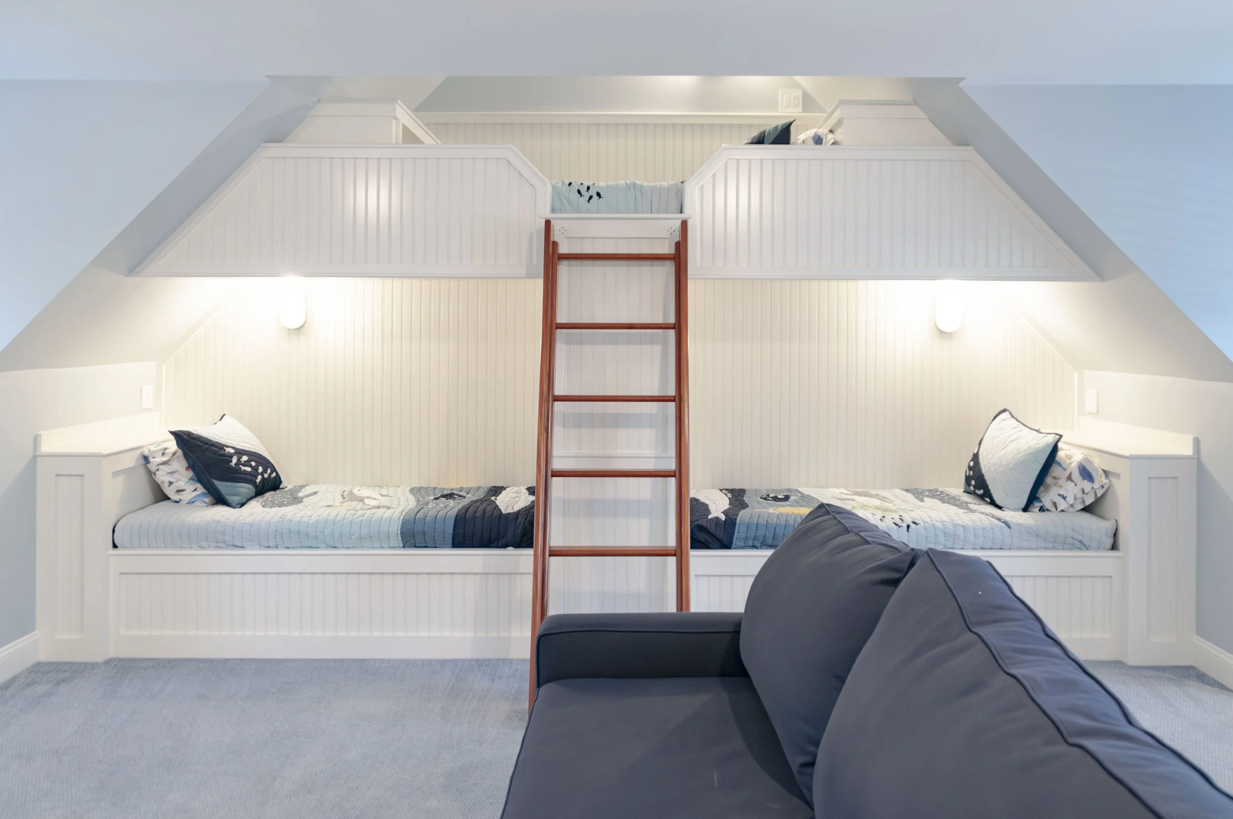 Cape Cod bunk room with built-in beds, loft ladder, beadboard millwork, and custom coastal home detailing.