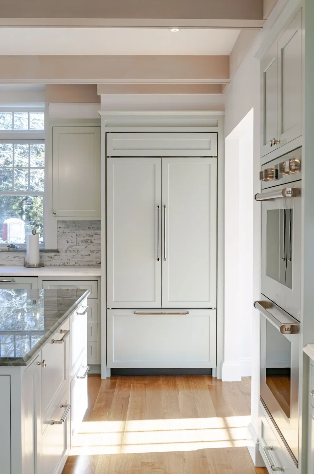 Integrated paneled refrigeration and polished wood floors highlight this high-end Cape Cod renovation kitchen.
