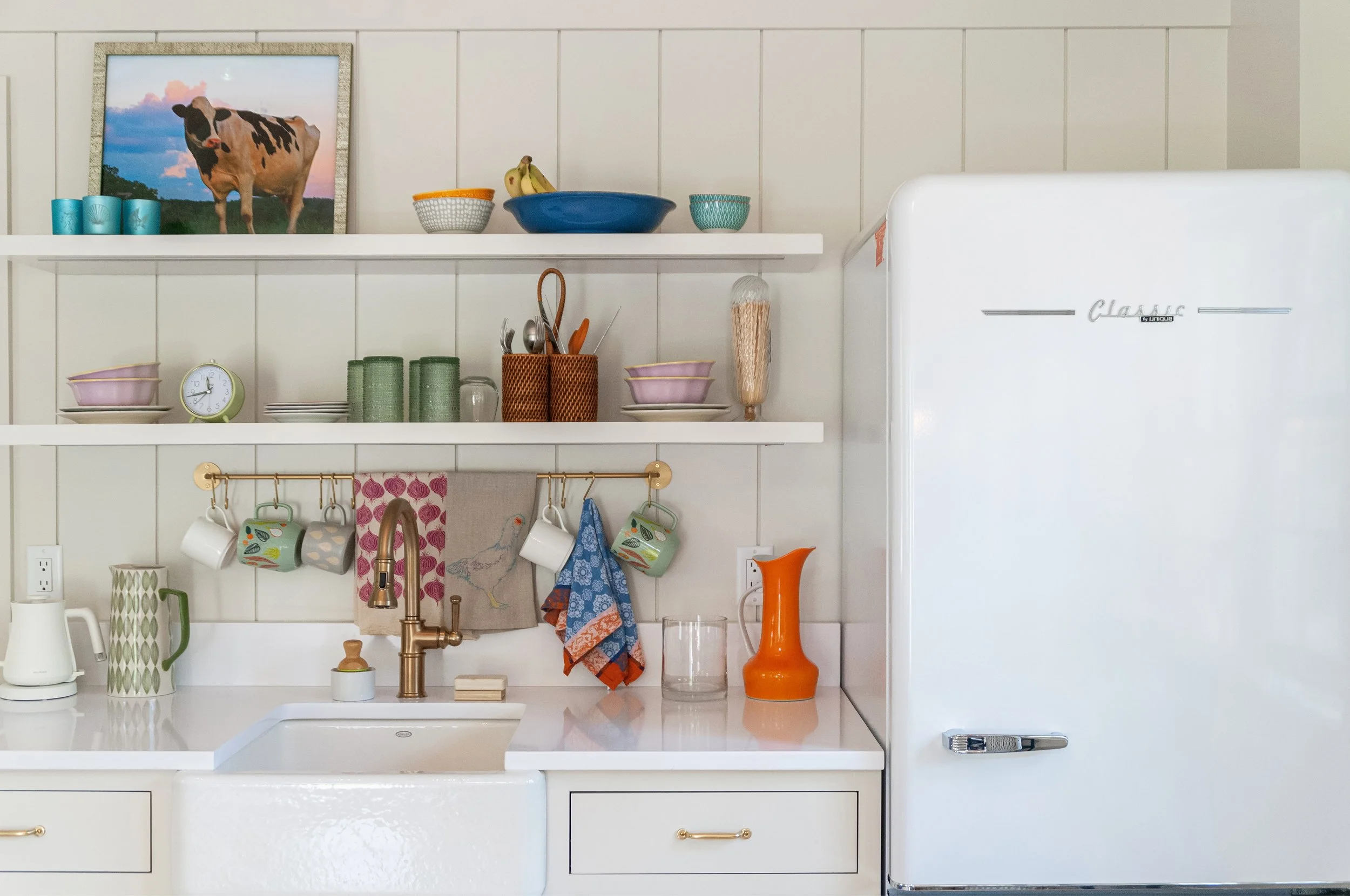 Colorful kitchen shelves and a vintage-style refrigerator bring character to this custom coastal home.