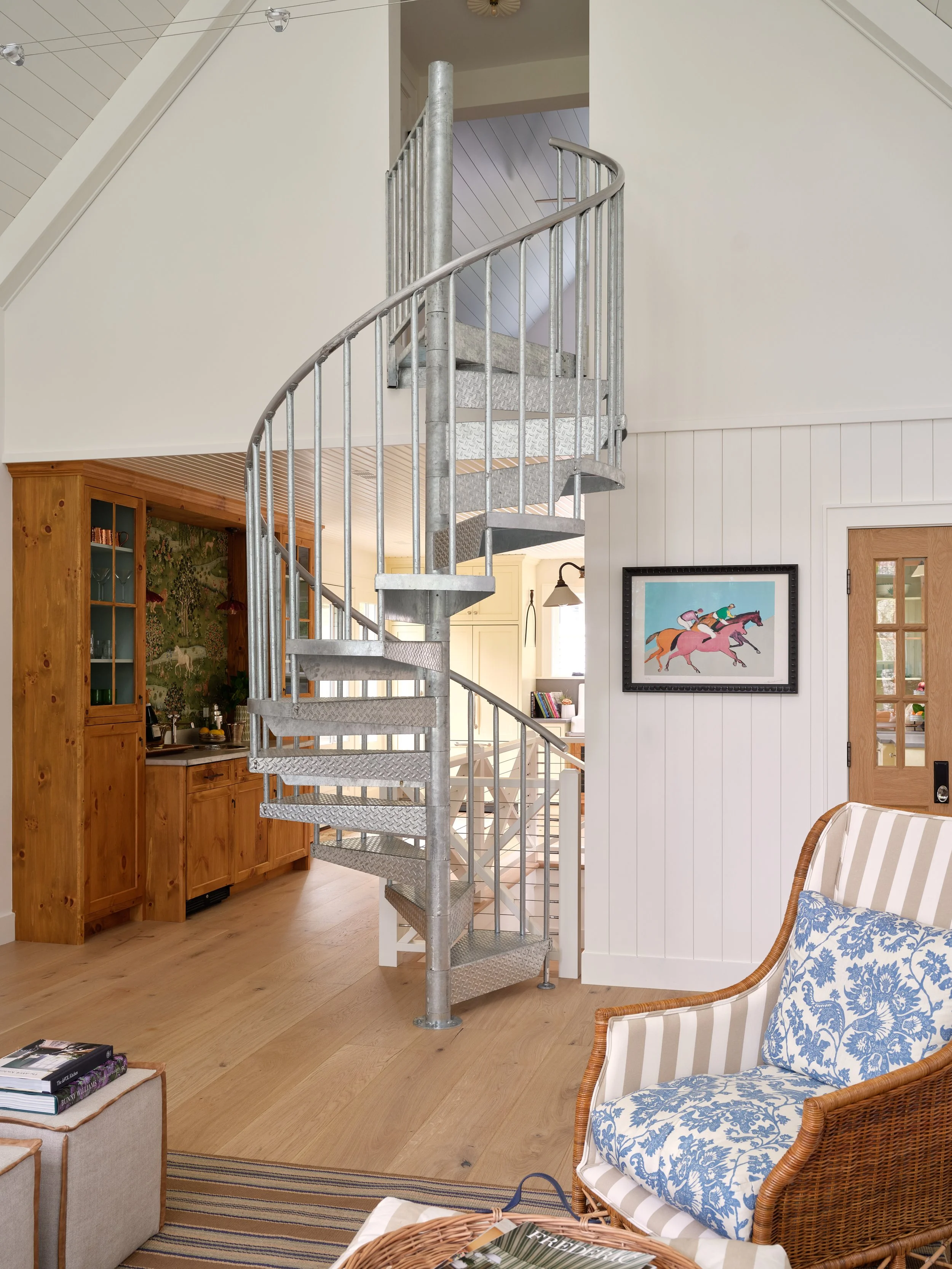 Curving through the center of this Sea View Builders guest house, the custom spiral staircase connects all three levels while complementing the Cape Cod interior design.