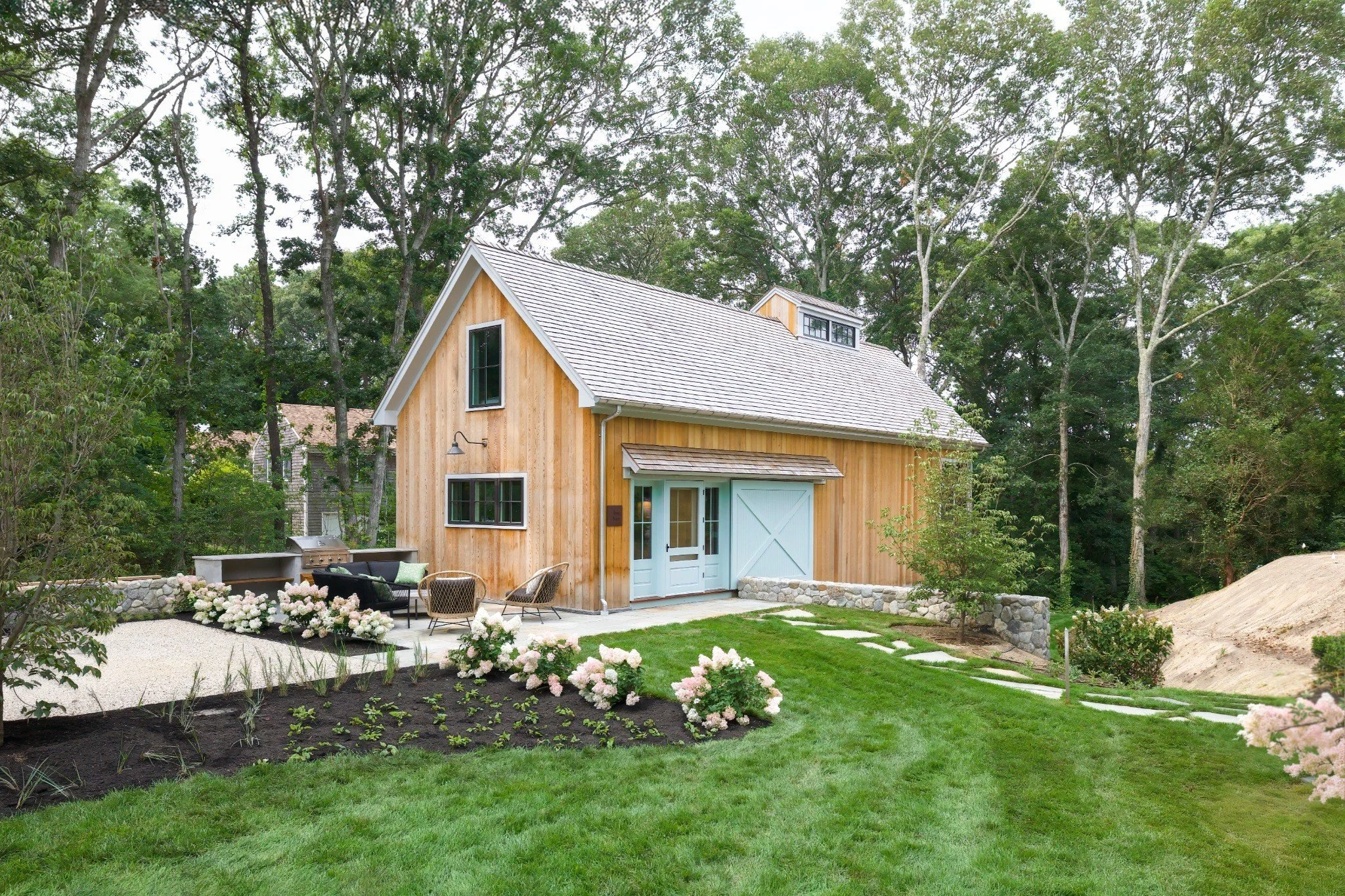 Blending classic barn architecture with Cape Cod design, this Sea View Builders project features custom wood siding, landscaped gardens, and a private backyard retreat.