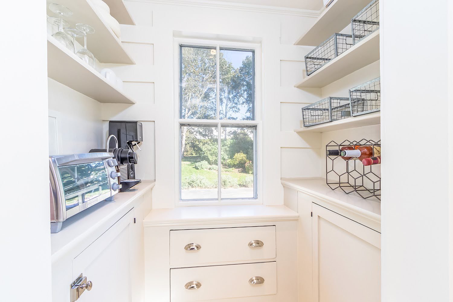 Built-in pantry shelving adds organized storage and natural light to this custom coastal home kitchen.