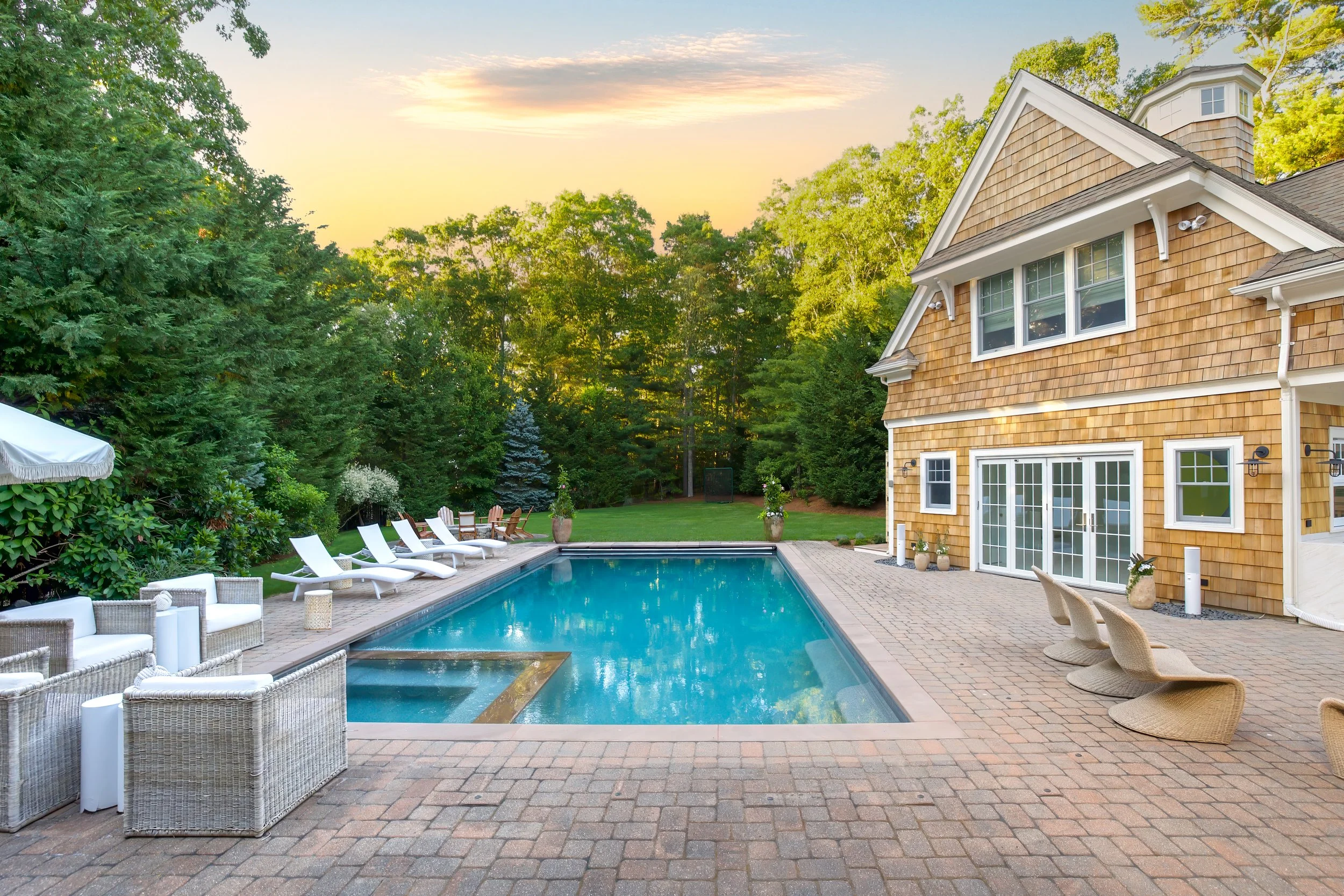 Sunset pool patio with shingled pool house, lounge chairs, and Cape Cod outdoor living details.