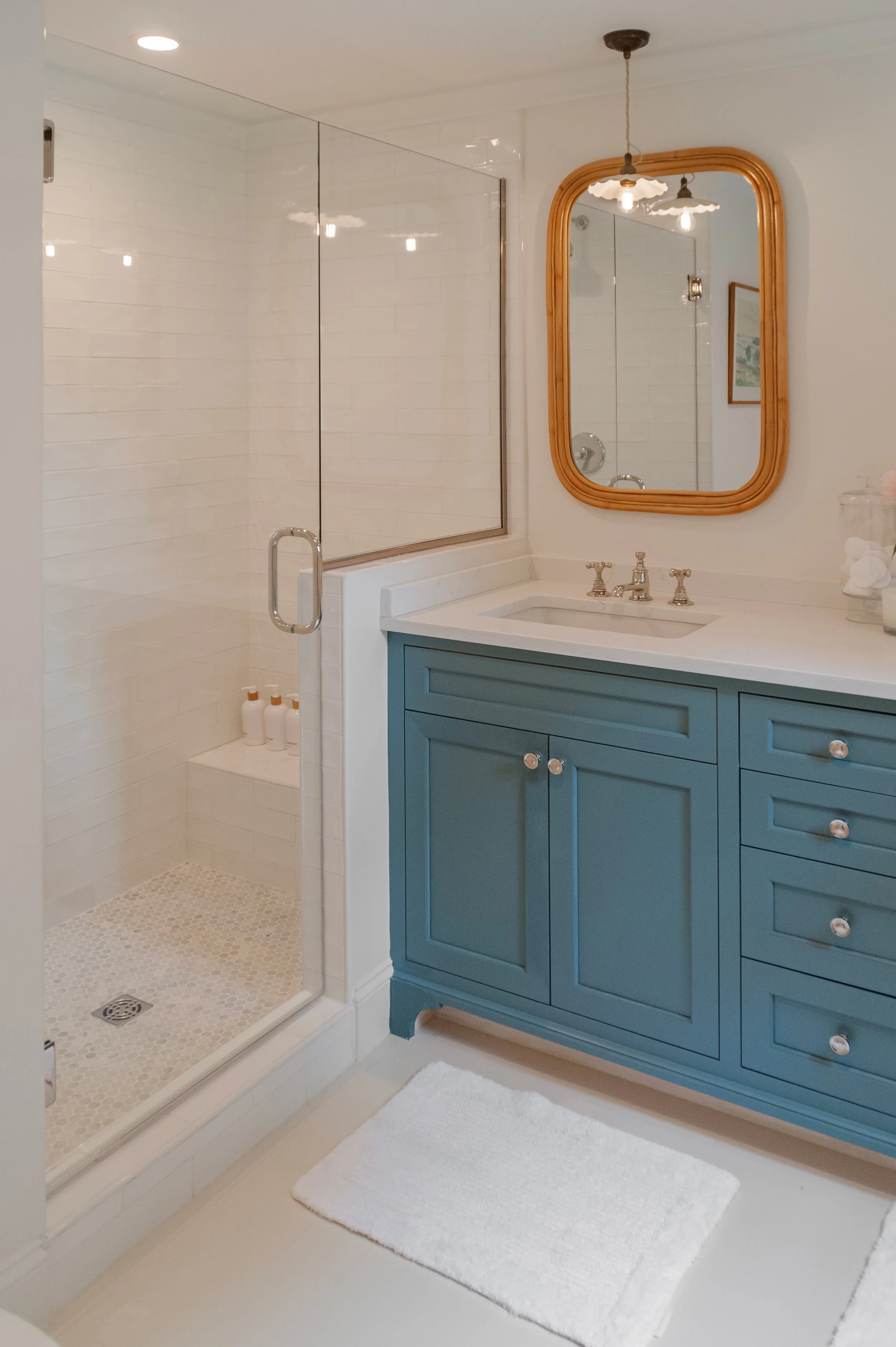 Blue vanity and glass shower in a Cape Cod bathroom renovation with white tile and coastal finishes.